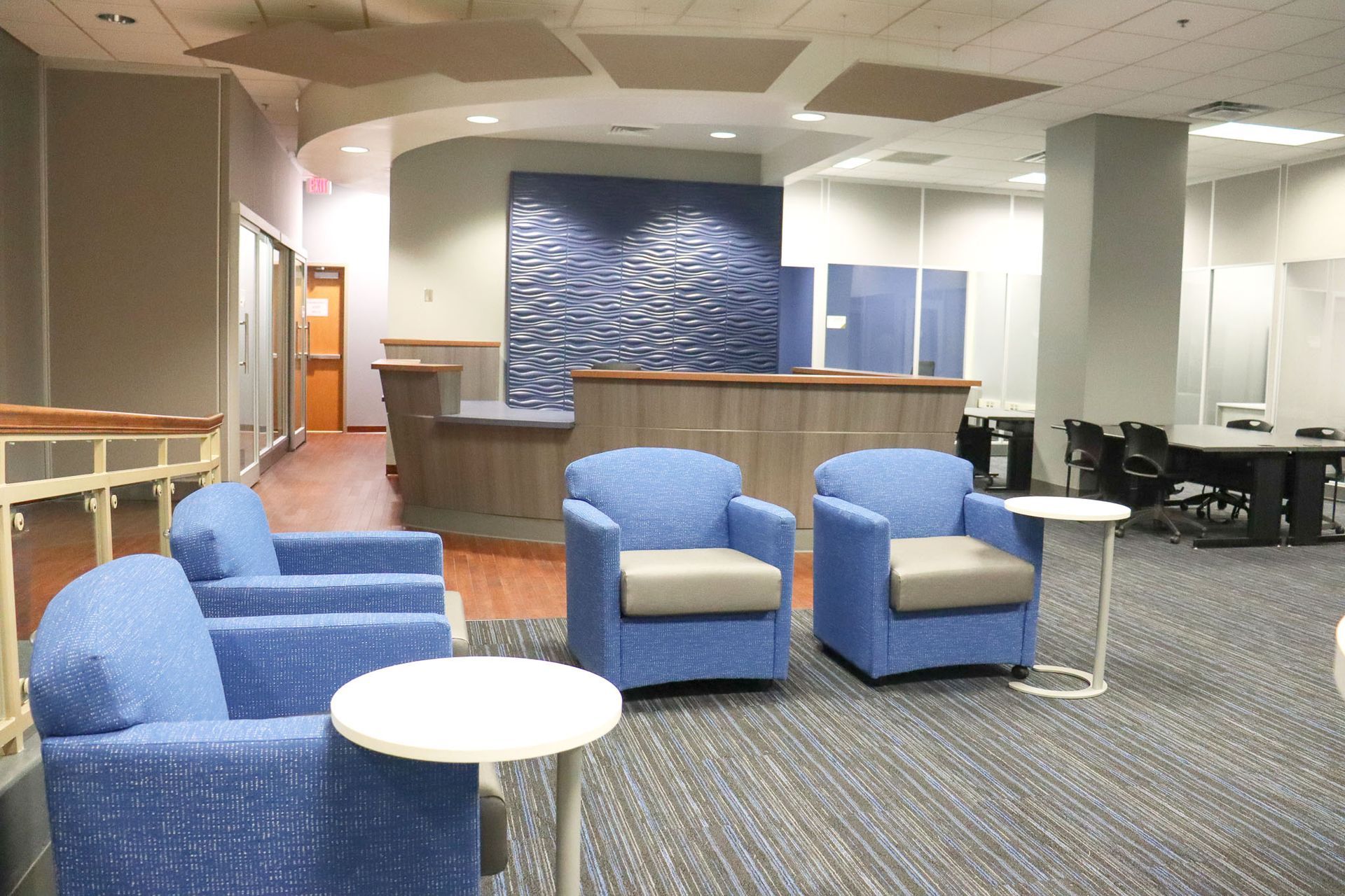 meeting space with four blue individual chairs and a reception desk