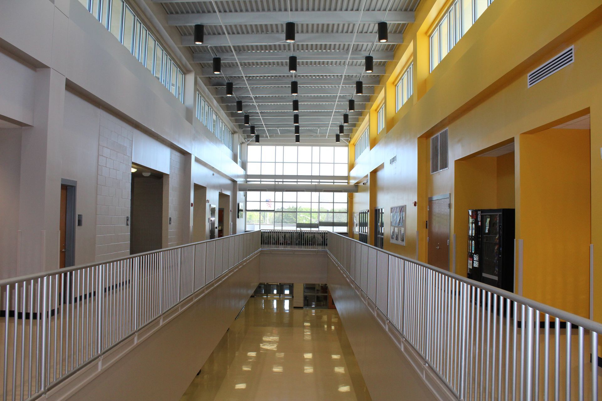 A long hallway with a white railing and yellow walls
