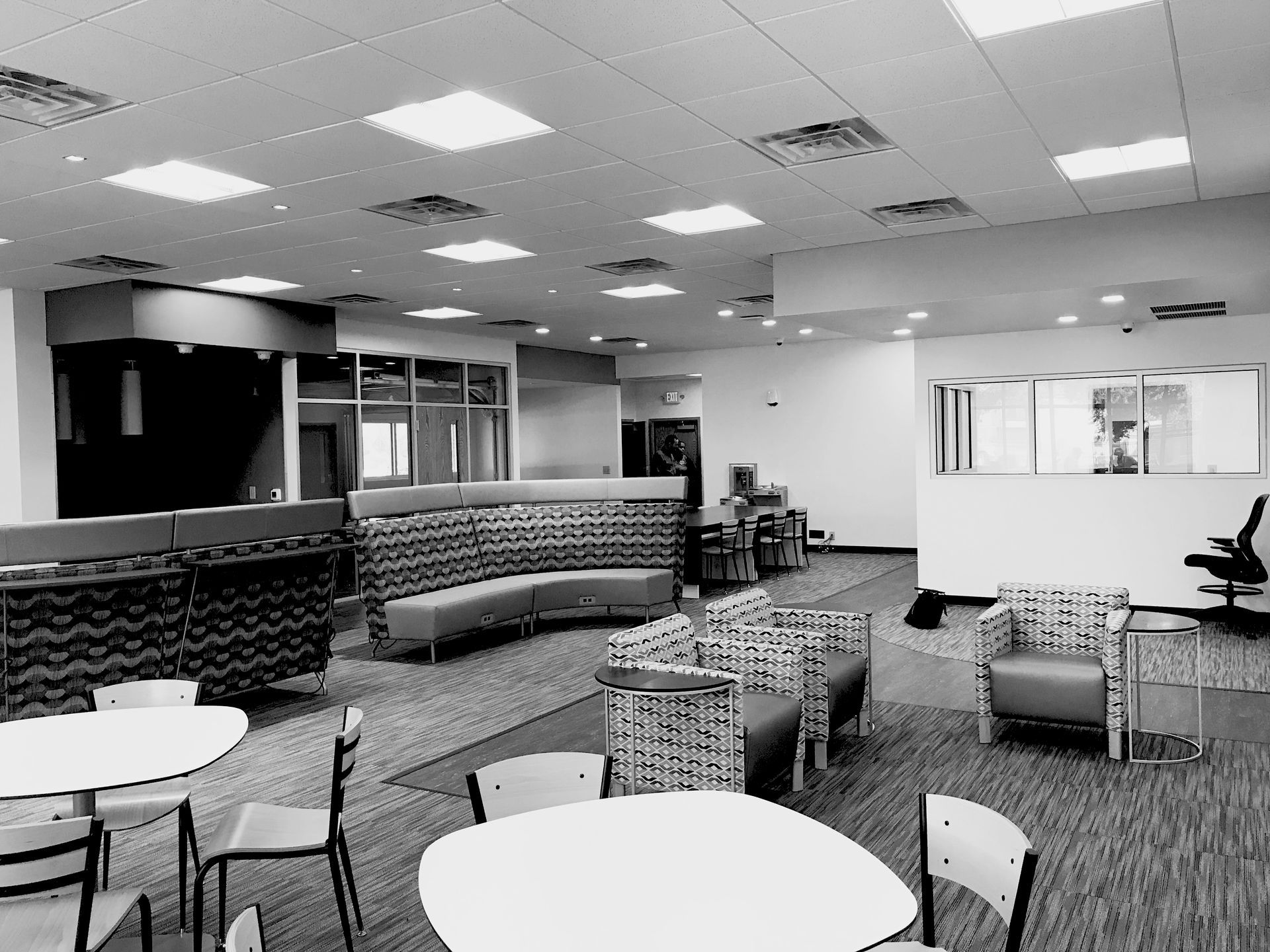 A black and white photo of a room with tables and chairs