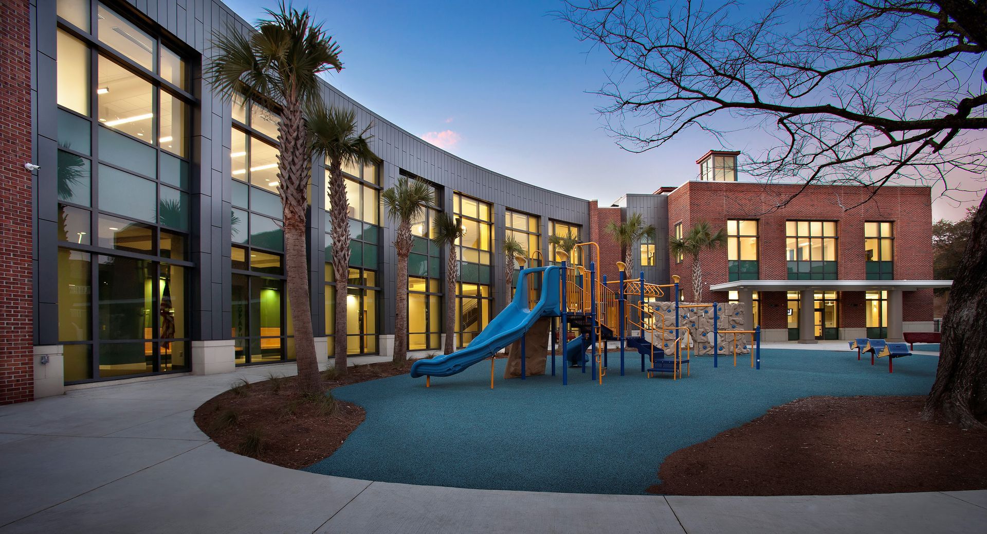 An elementary school with a playground in front of it at dawn