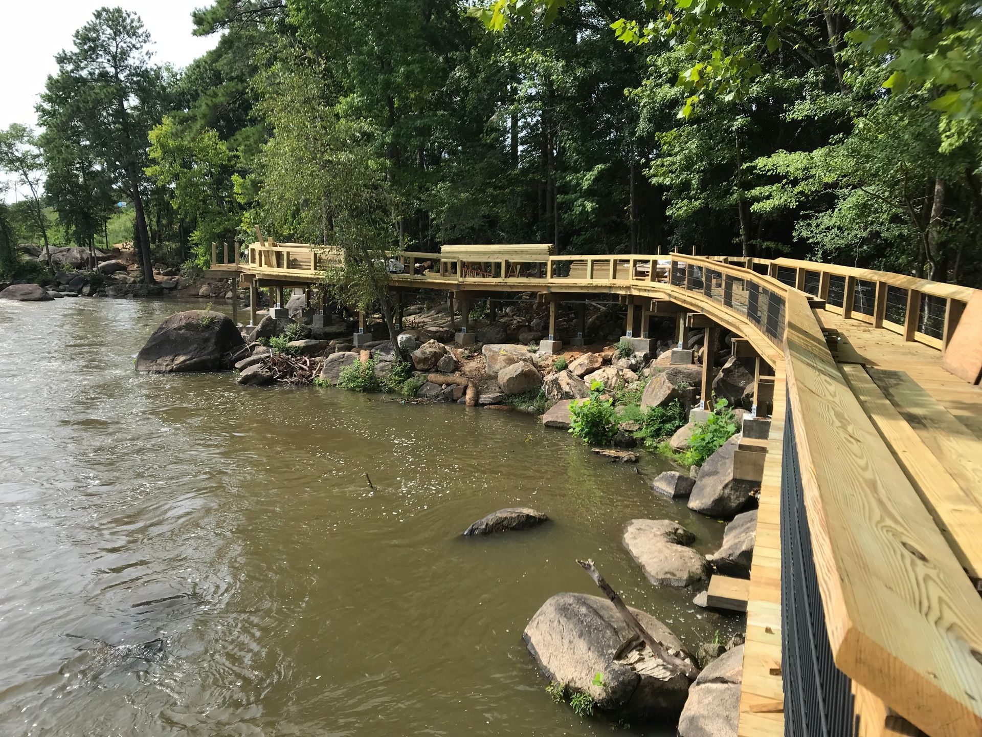 A wooden bridge over a river with trees in the background