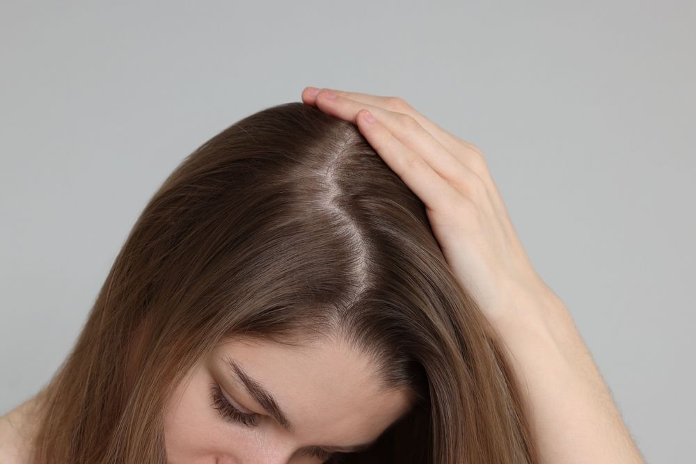 A woman is touching her hair with her hand.