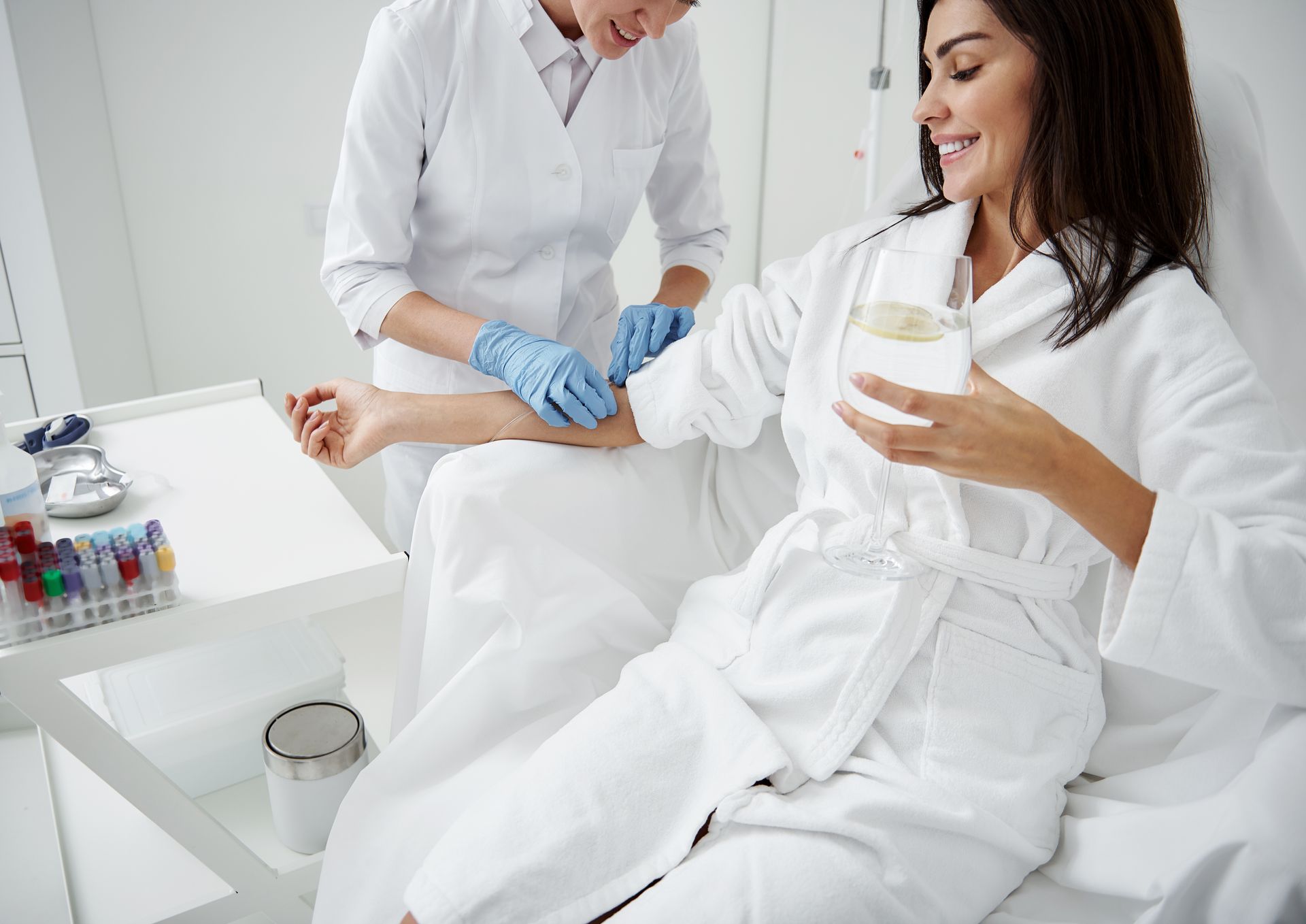 A woman is getting an injection in her arm while holding a cup of coffee.