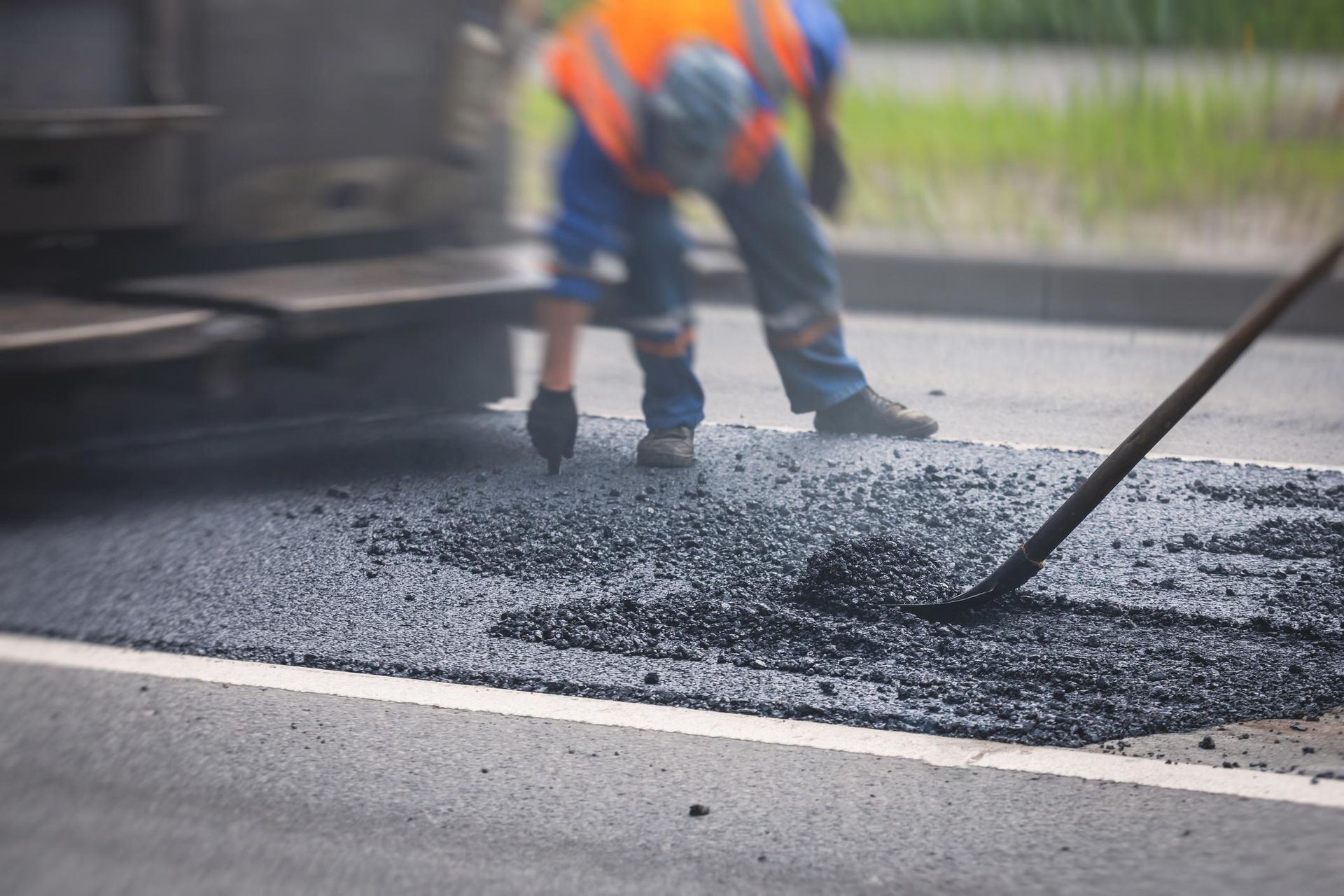 A man is seen working on asphalt for parking lot pavement restoration in Blue Springs, MO.