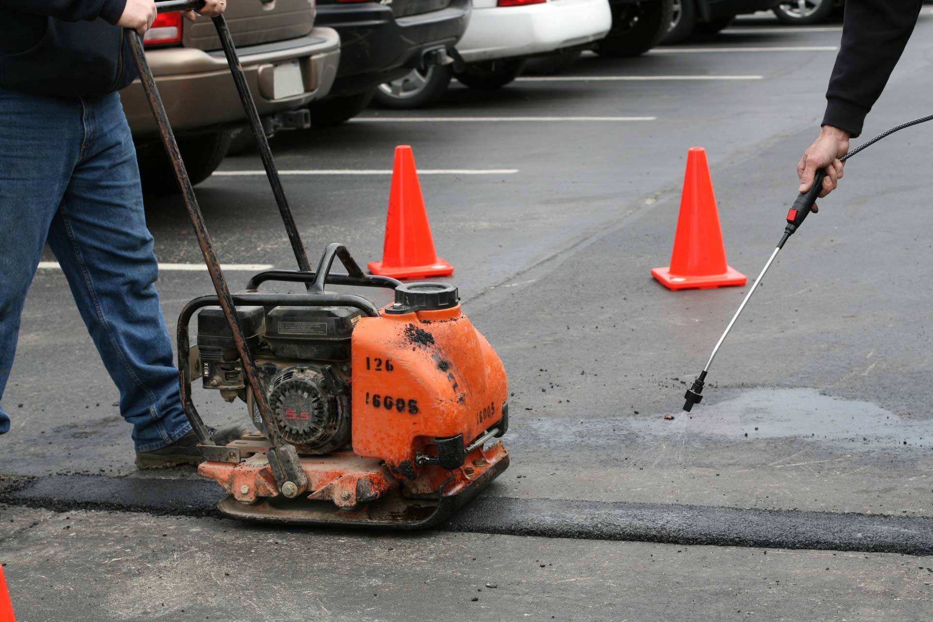 Parking lot asphalt repair team resurfacing damaged area for smooth and durable surface — Kansas, MO — J & B Asphalt & Paving