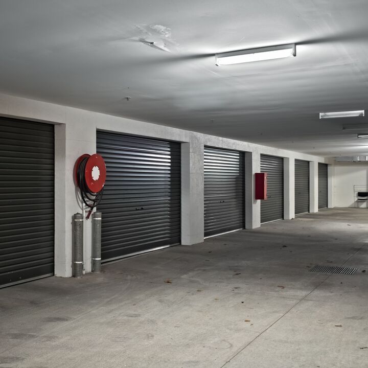 Row of closed garage doors in a concrete parking structure with a fire hose reel.