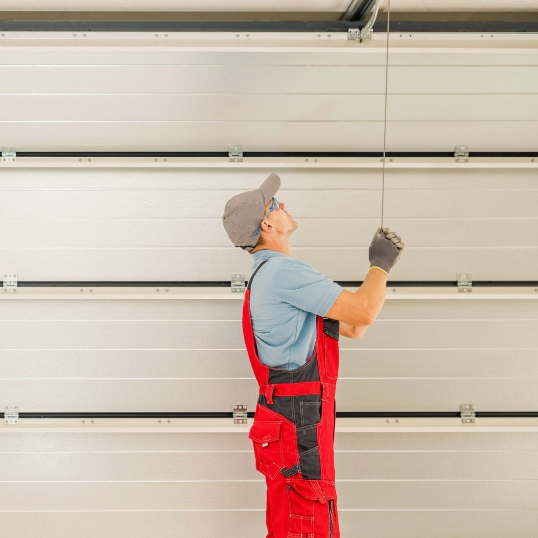 Person in red overalls inspecting garage door cables.