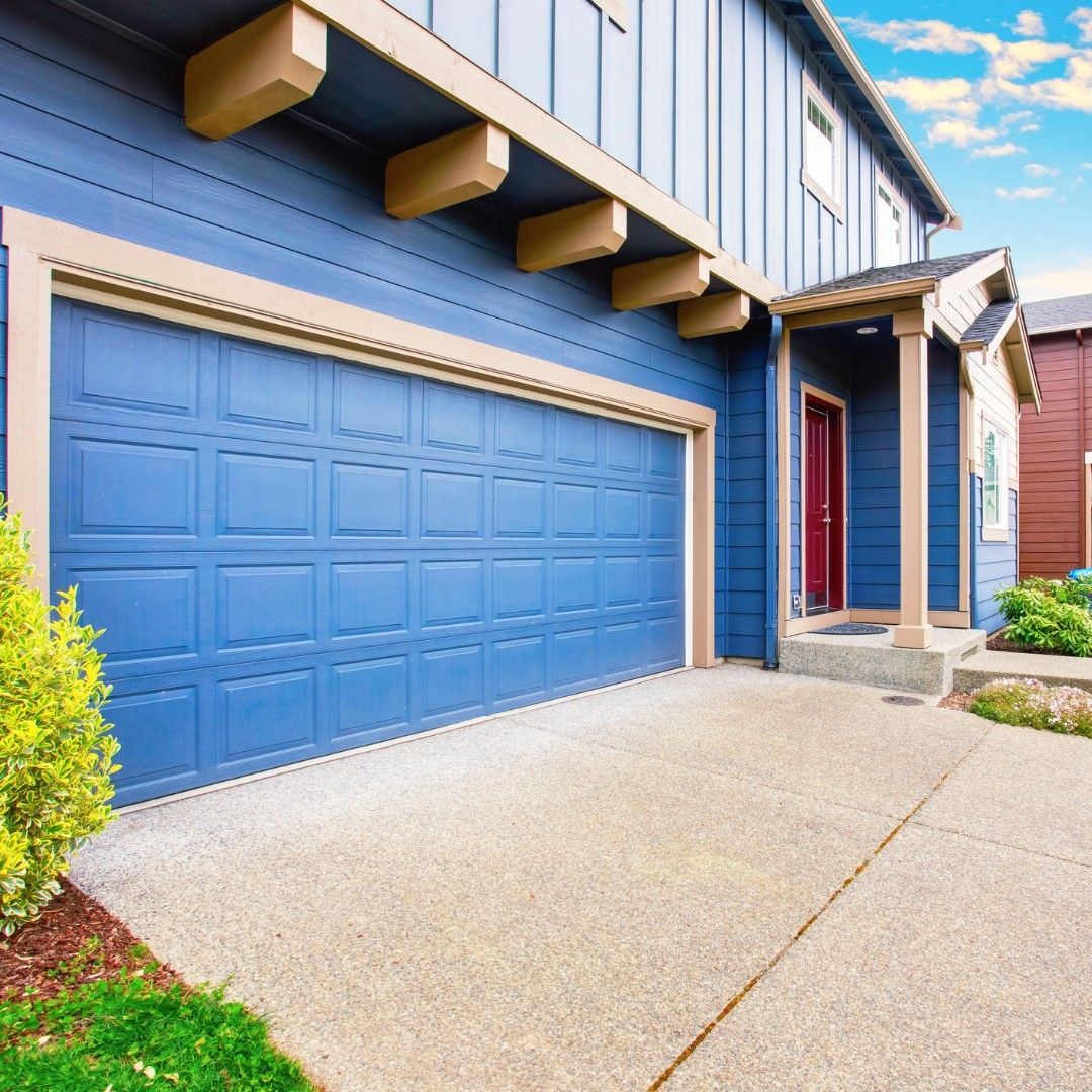 Blue house with blue garage door and concrete driveway.