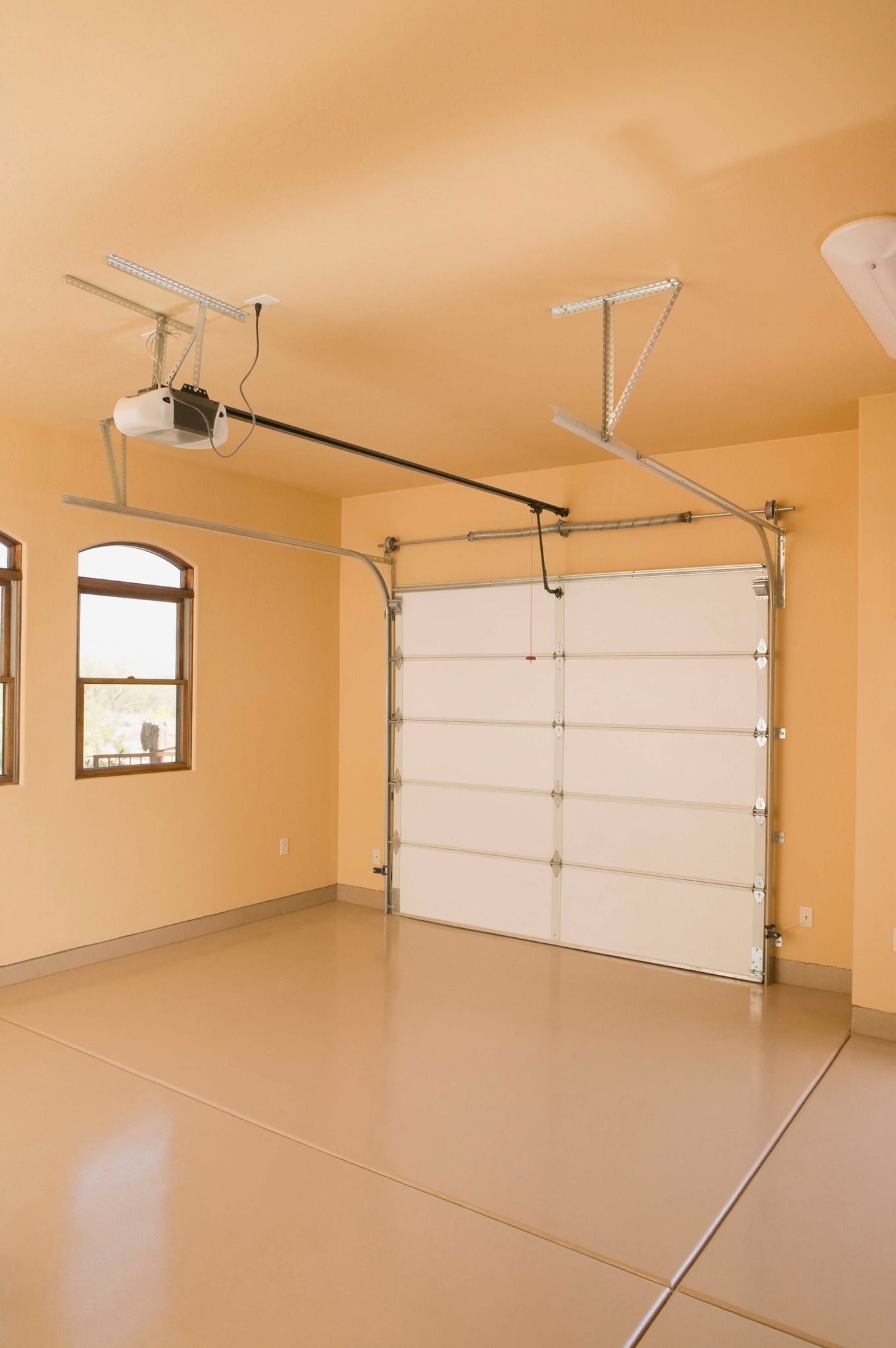 Empty garage with closed white door, beige walls, and light-colored floor.