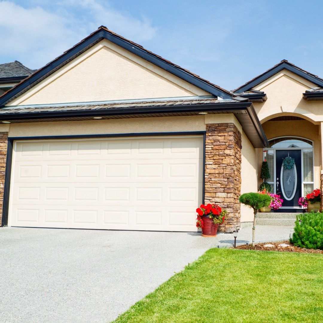Beige house with a two-car garage, stone accents, and a blue front door. Green lawn in the foreground.