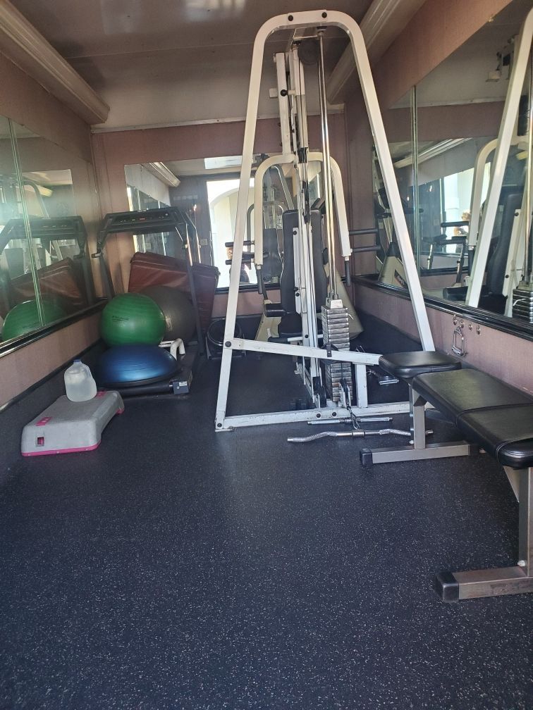 A gym with a treadmill , exercise balls , and a bench.