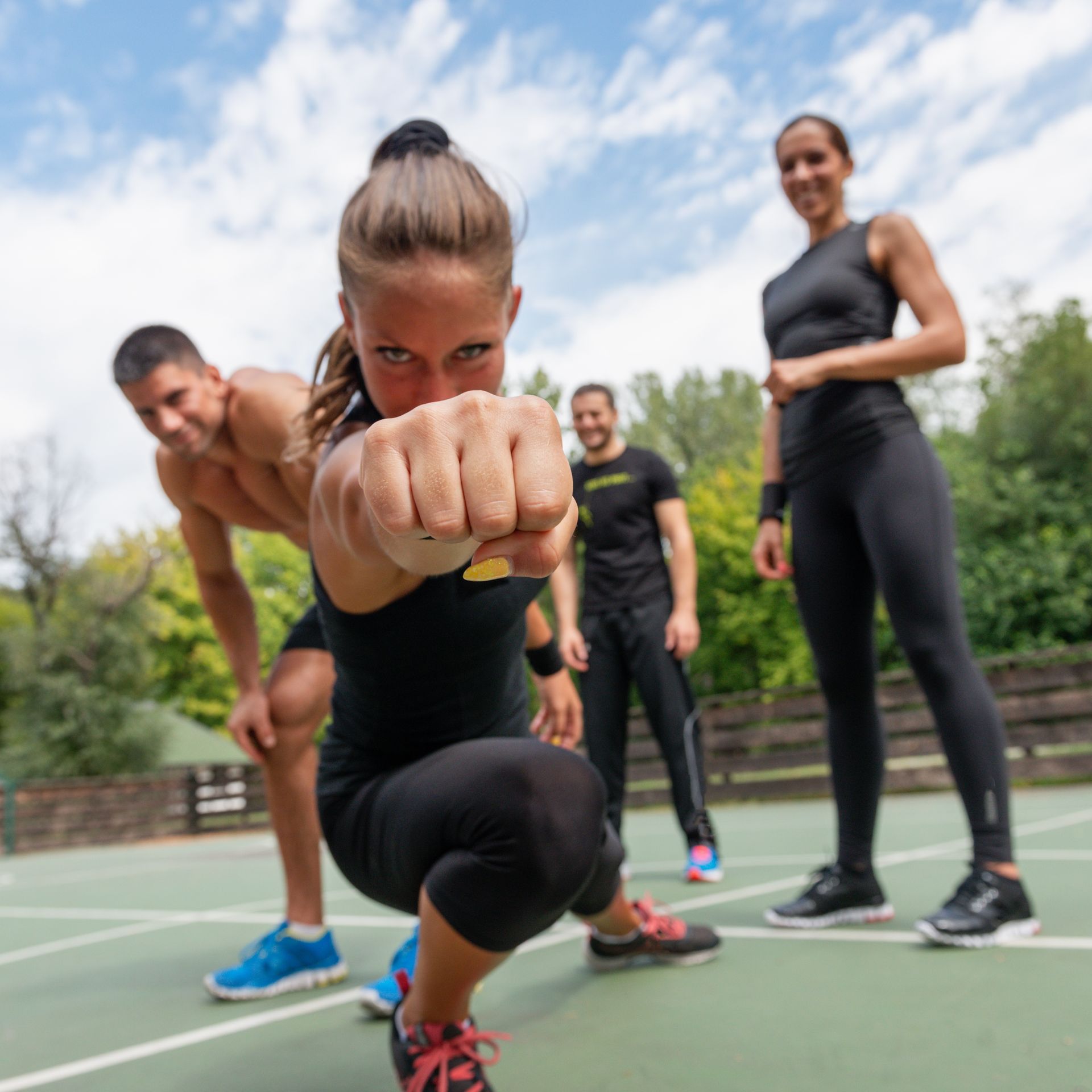 A group of people are doing exercises on a tennis court.