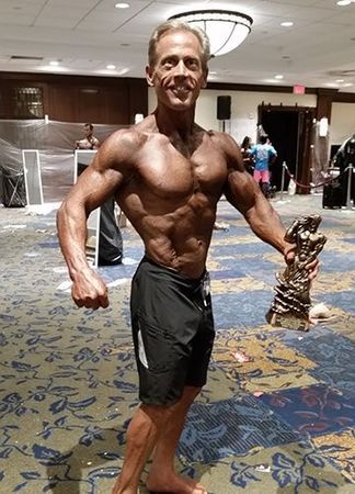 A man is standing in a room holding a trophy.