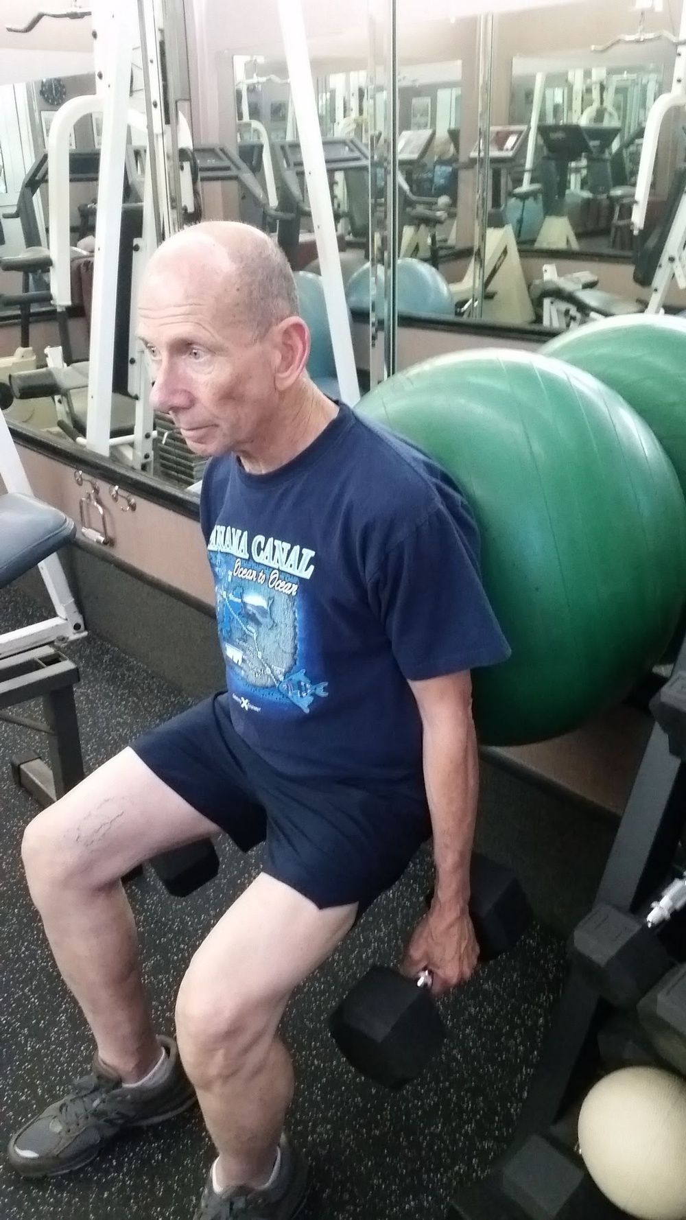 A man is squatting with a dumbbell in a gym.