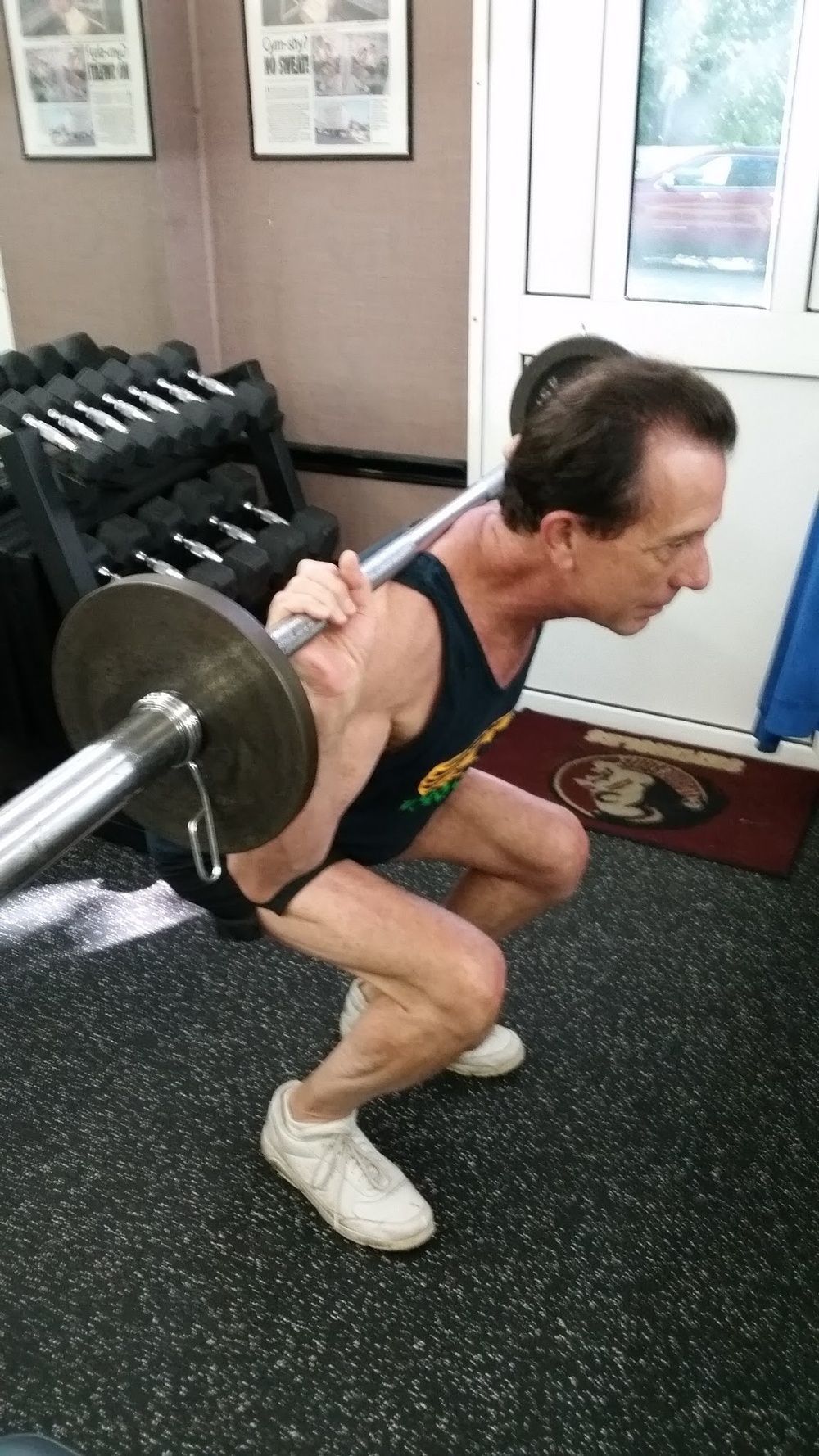 A man is squatting with a barbell in a gym.