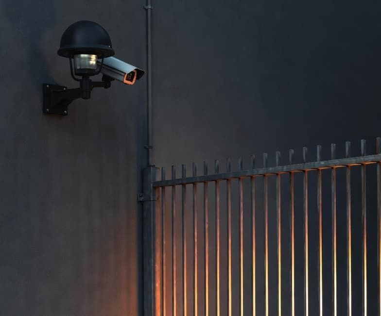 A dimly lit area with a security camera and a fence
