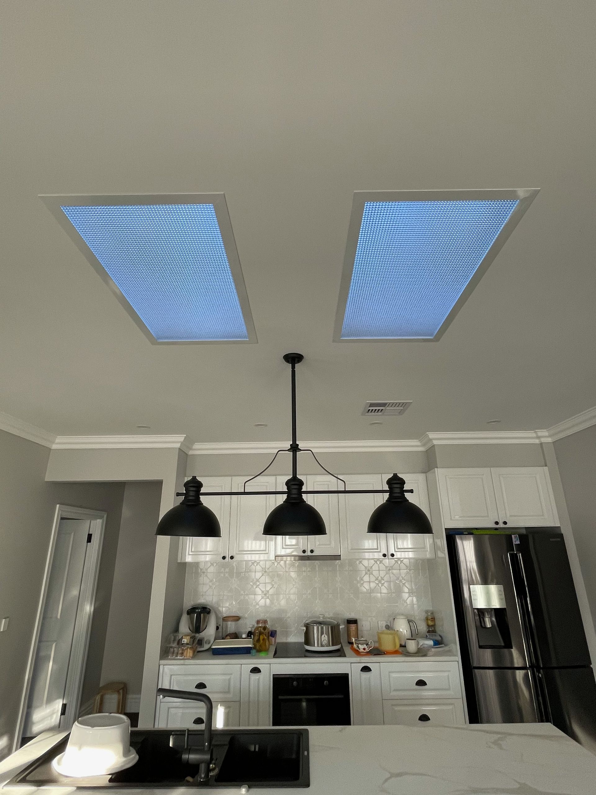 A kitchen with two skylights and a refrigerator.