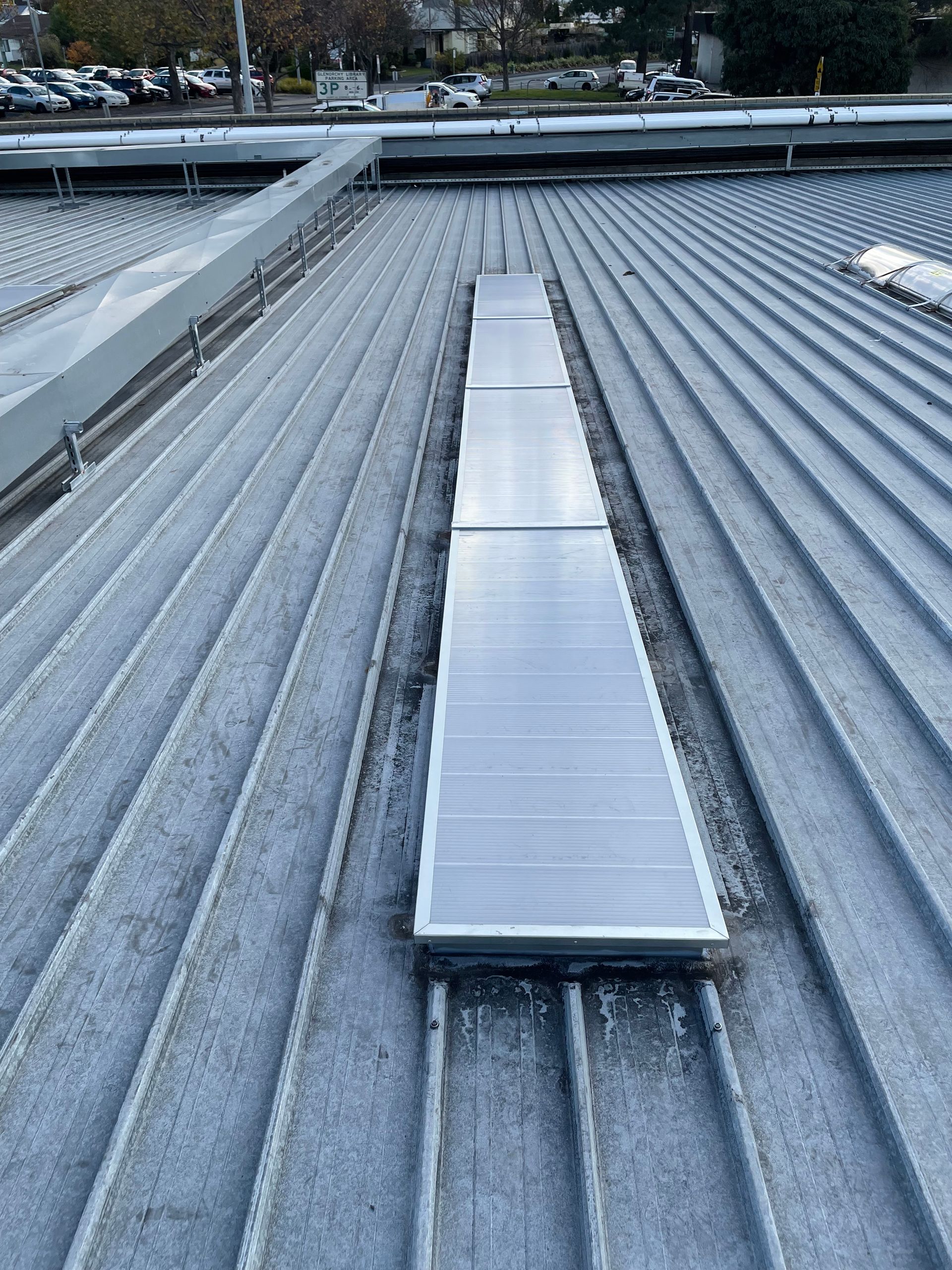 A gray roof with a clear skylight on it.