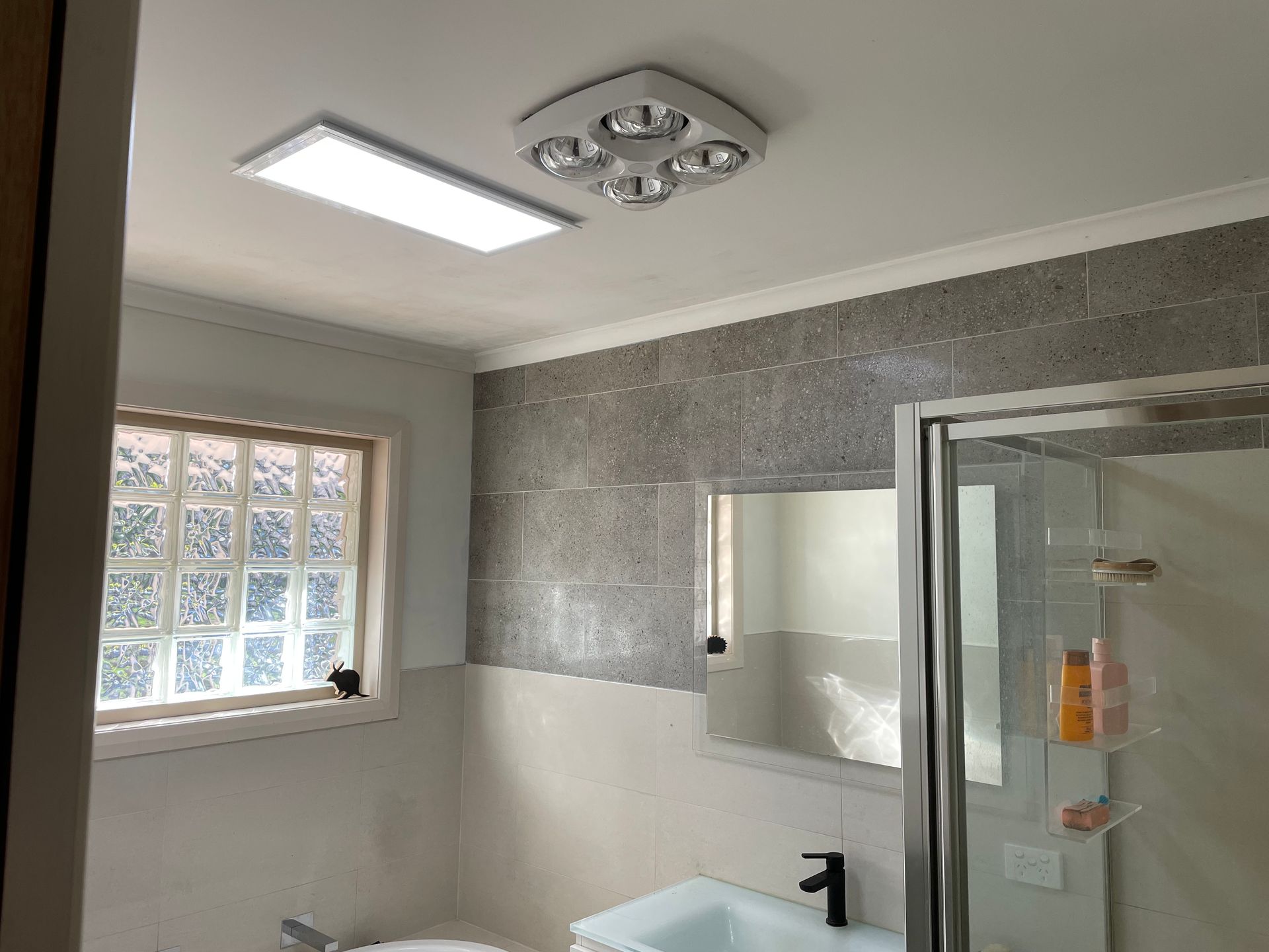 A bathroom with a sink , toilet , mirror and shower.