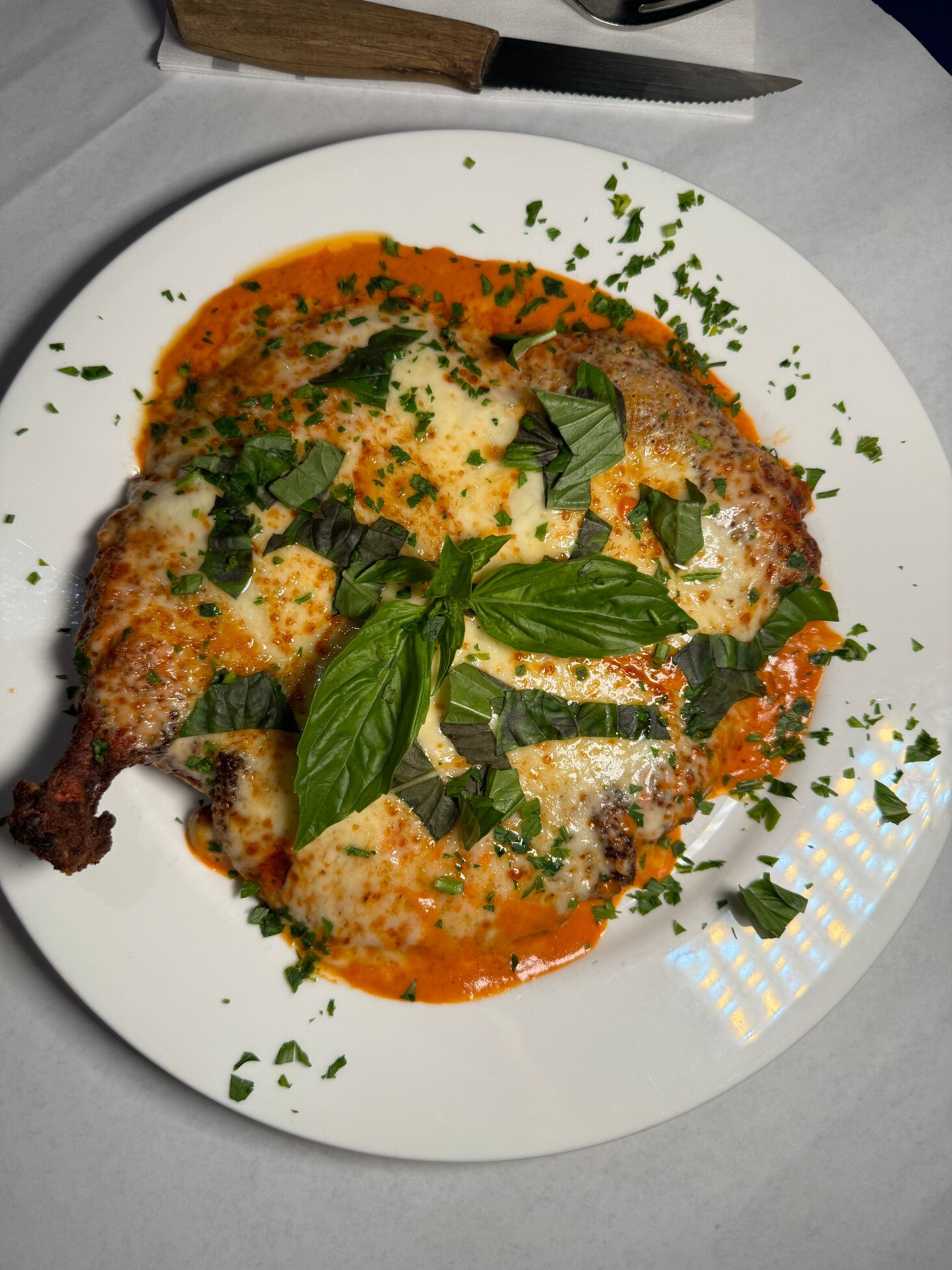 A white plate topped with a piece of meat and sauce