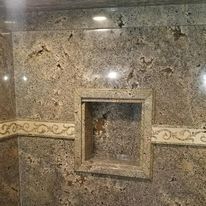 A bathroom with a marble wall and a shower niche.