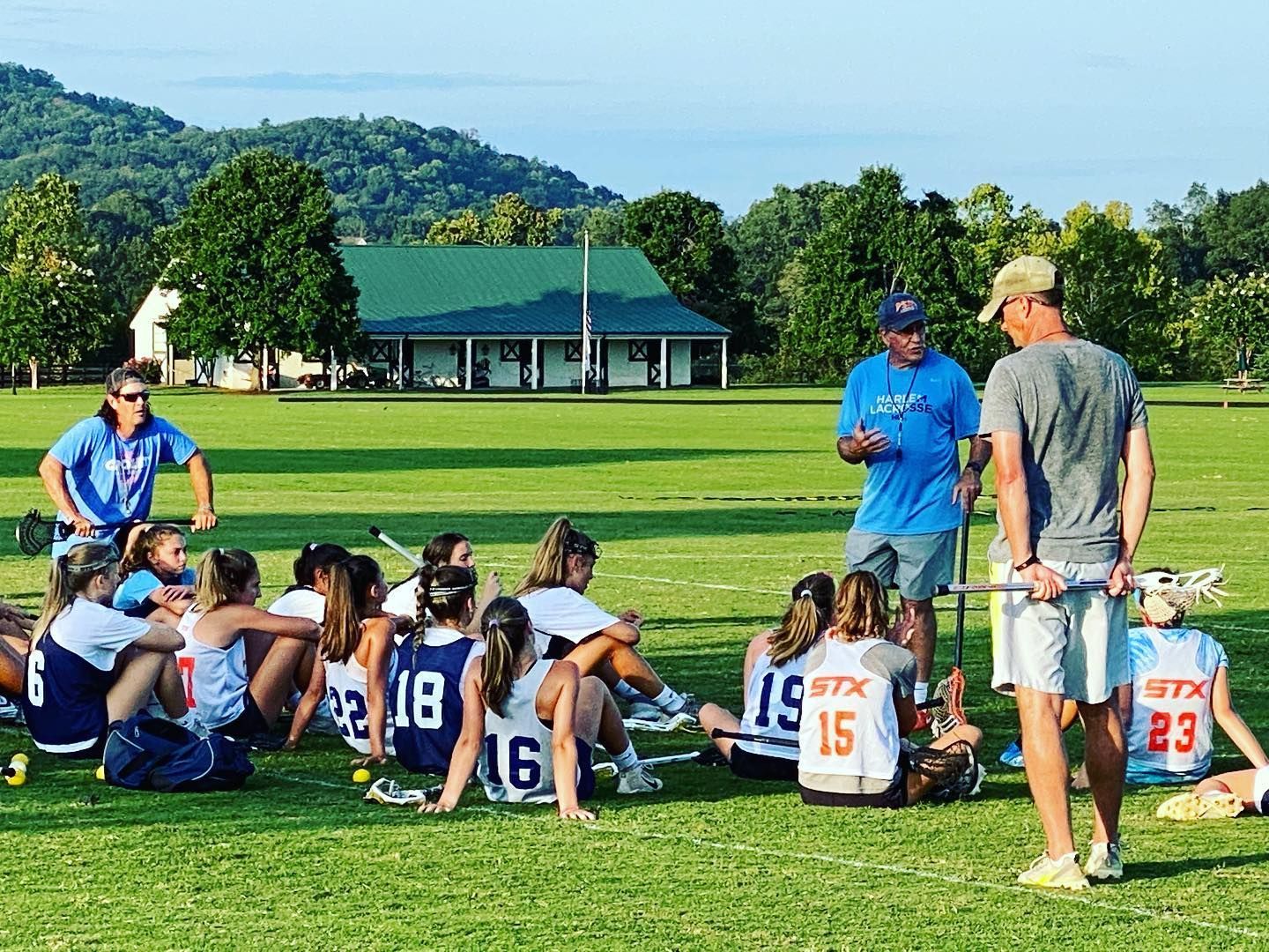 Picture of team sitting on ground listening to coaches speak