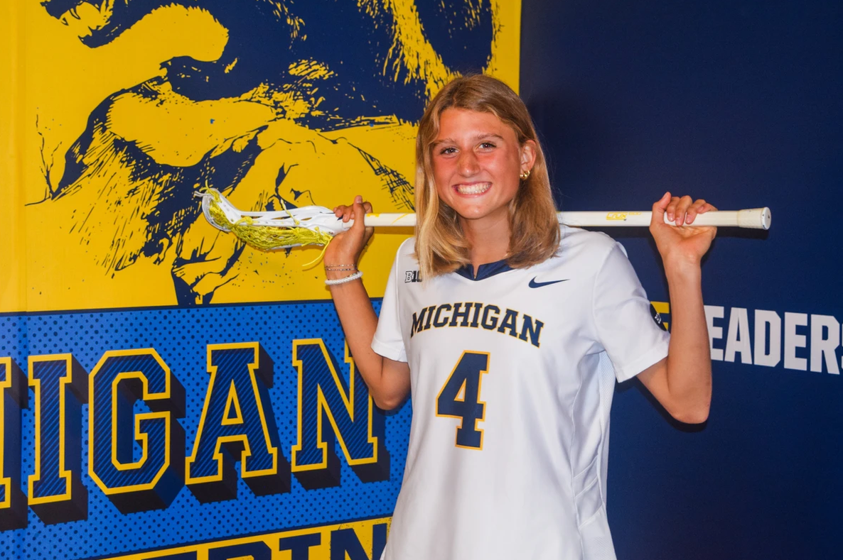 Athlete commits to University of Michigan lacrosse, wearing maize and blue uniform with block M graphic