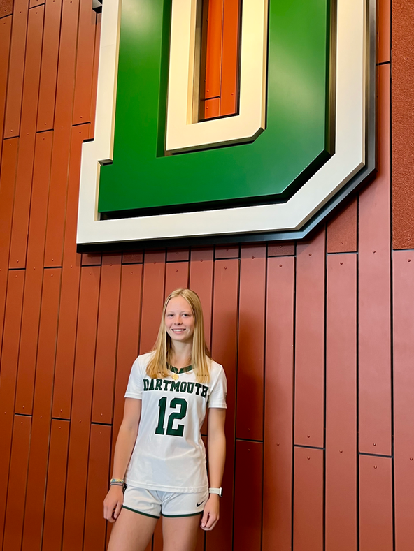 Athlete wearing Dartmouth sweatshirt standing in front of large green Dartmouth
