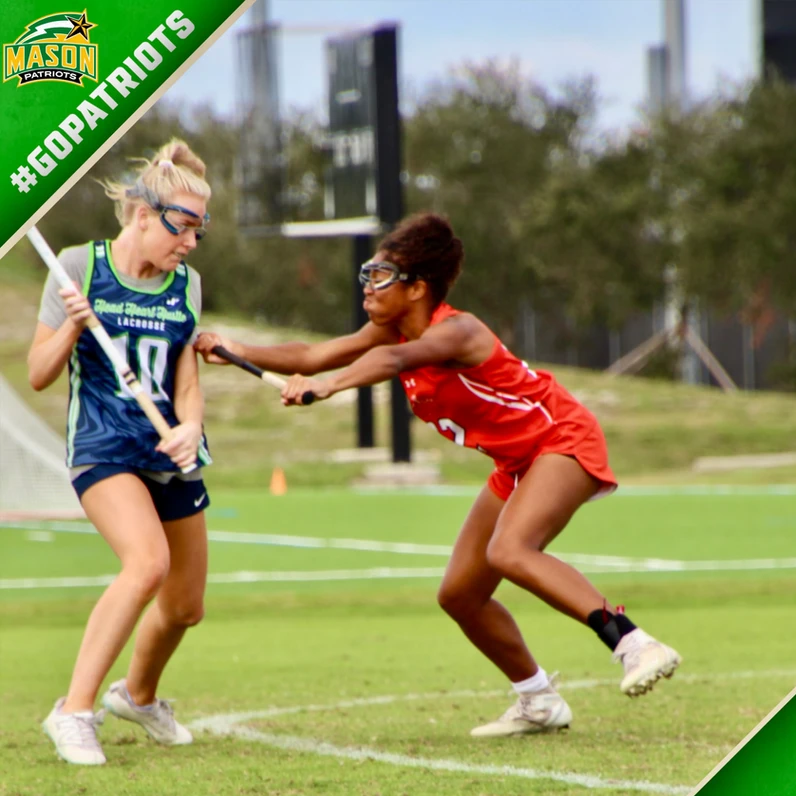 Two female lacrosse players in game action, player in red defending against opponent in blue and green