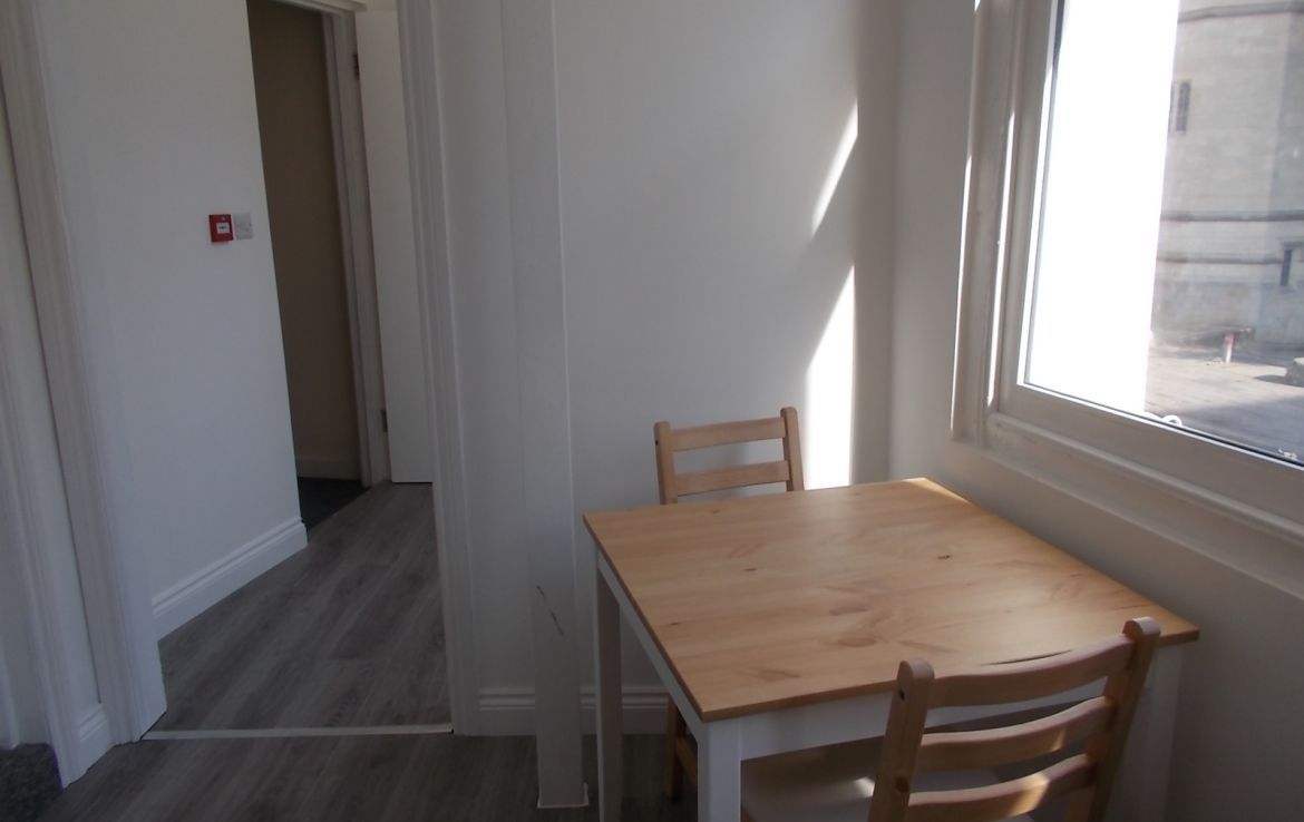 a wooden table and chair in a room with a fire extinguisher on the wall