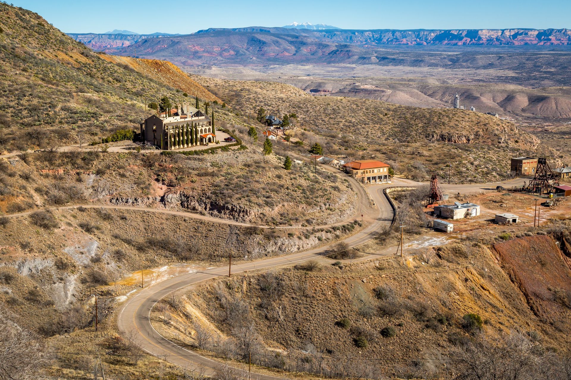 An aerial view of a desert landscape with a dirt road going through it.