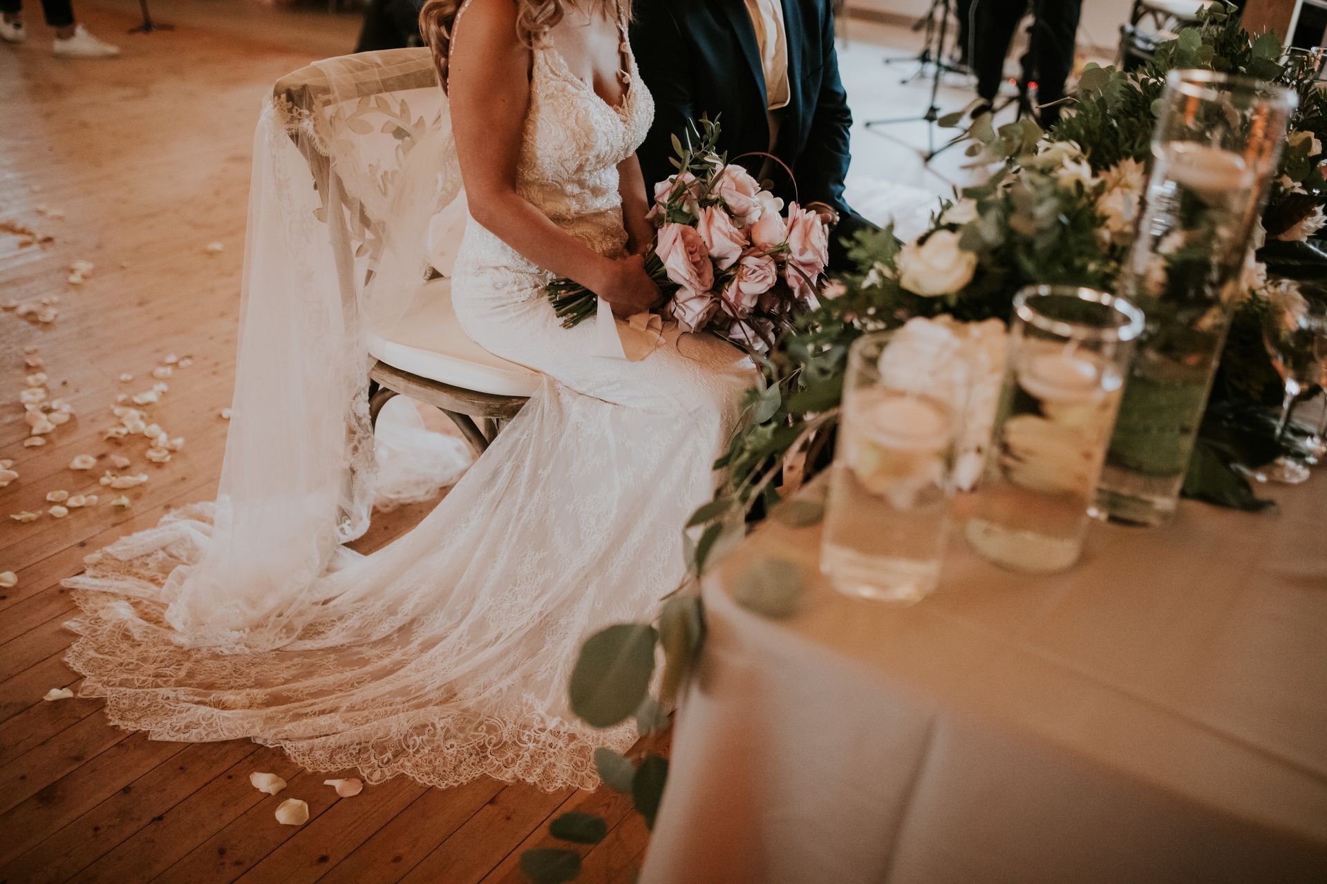 A bride and groom are sitting at a table at their wedding reception.