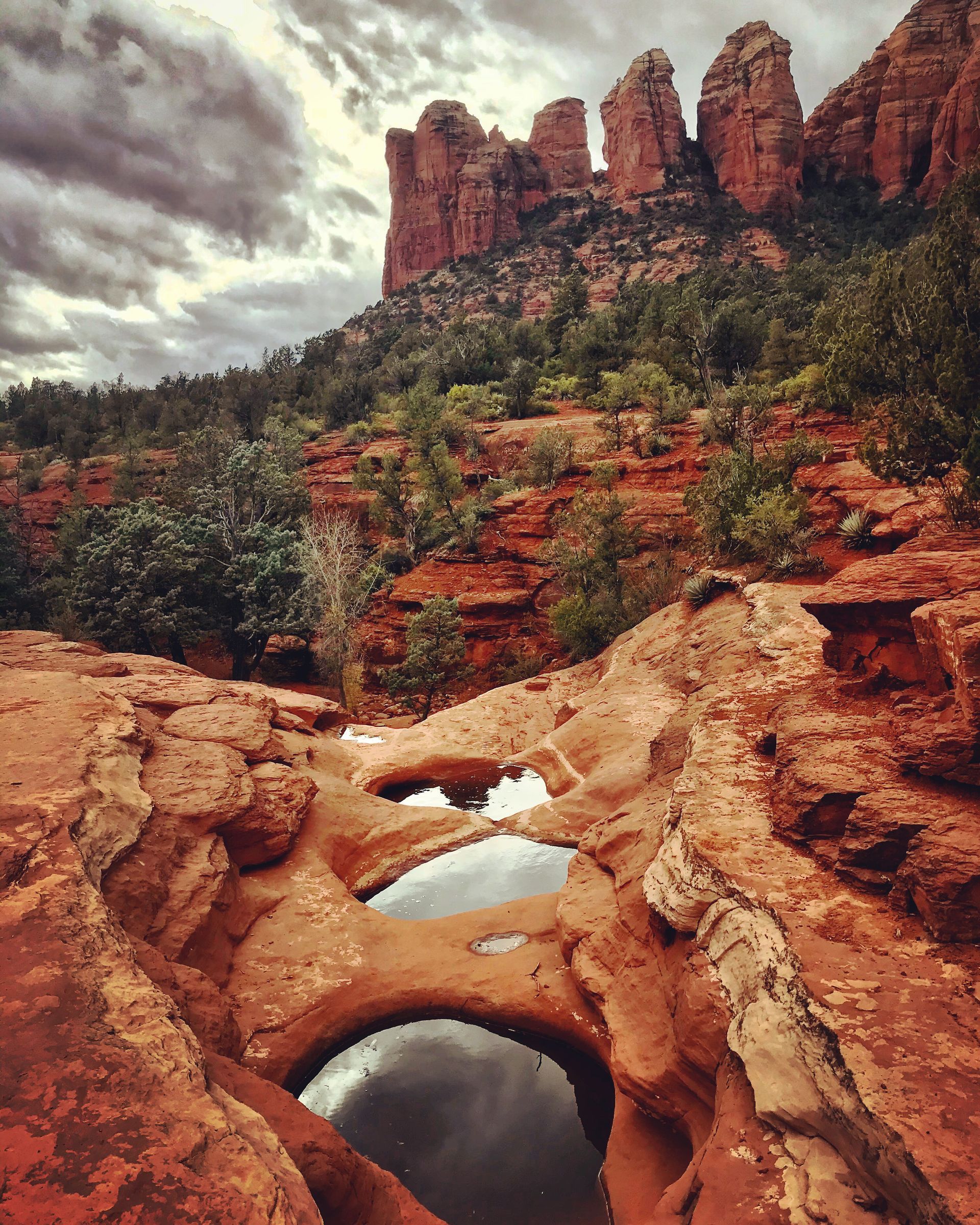 the seven sacred pools with a view of the red rocks and foliage behind it