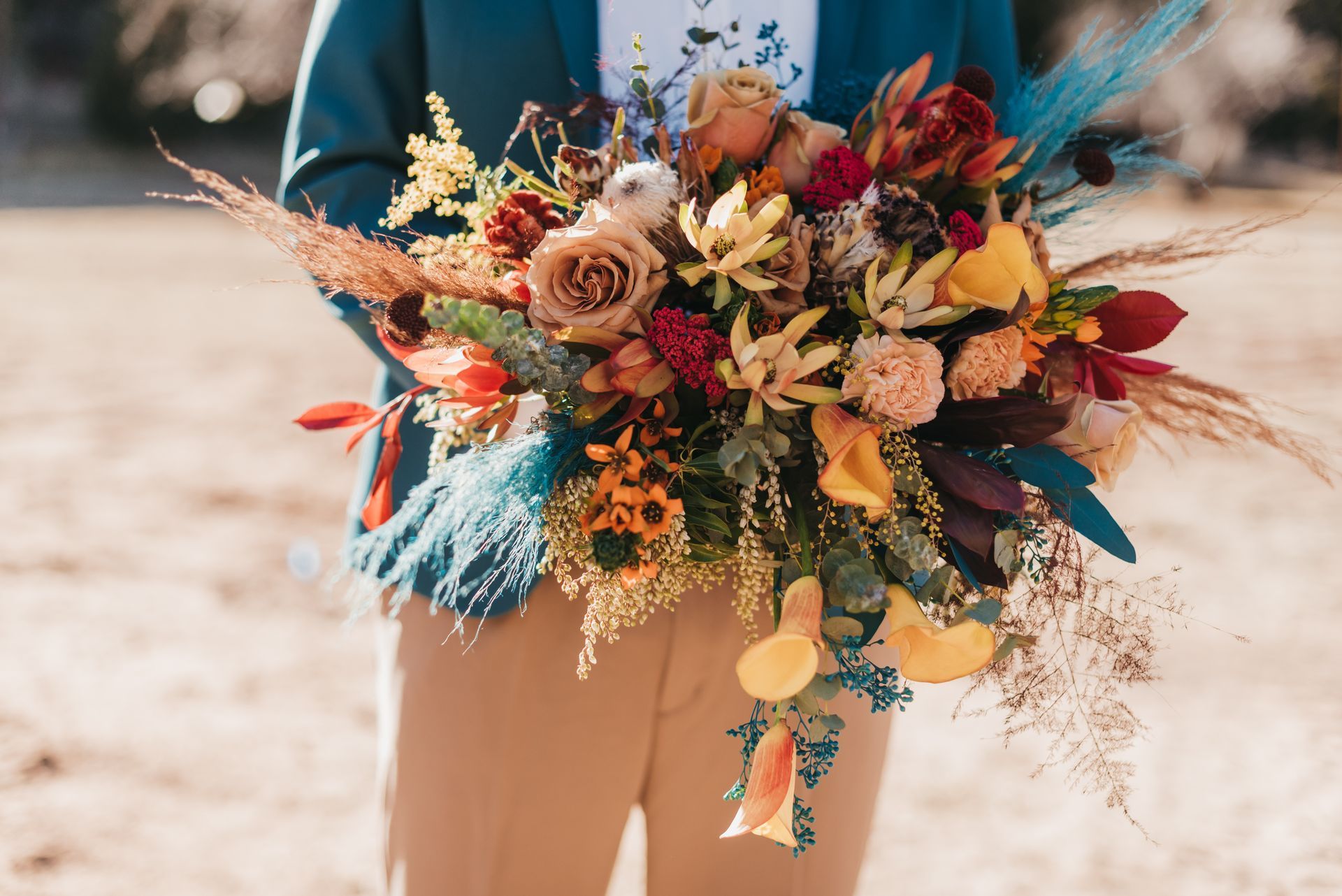 A man is holding a bouquet of flowers on the beach.