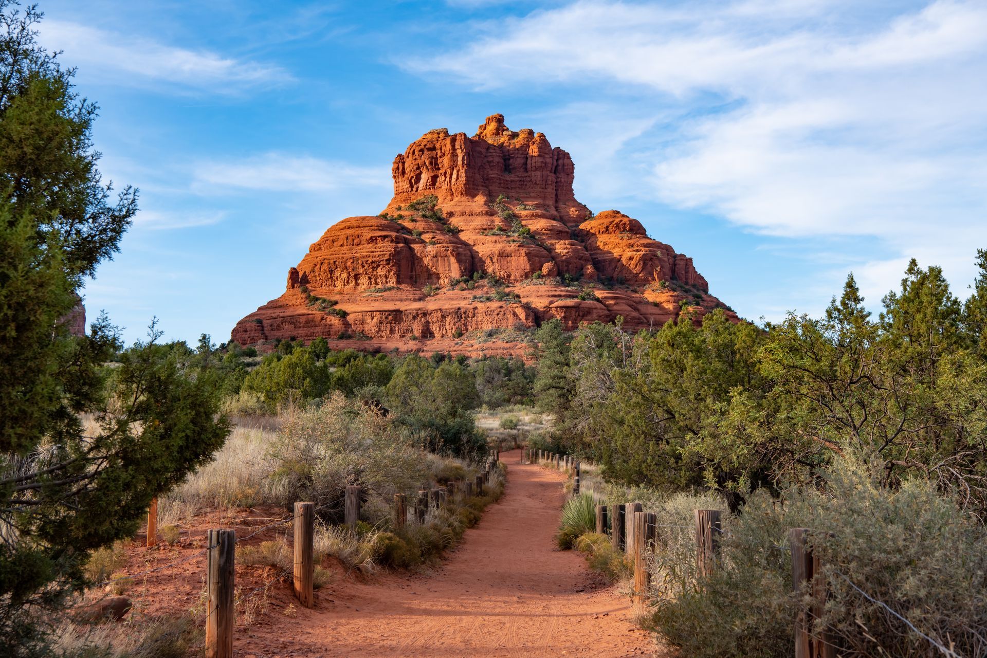 A dirt path leading to a large rock formation in the desert.