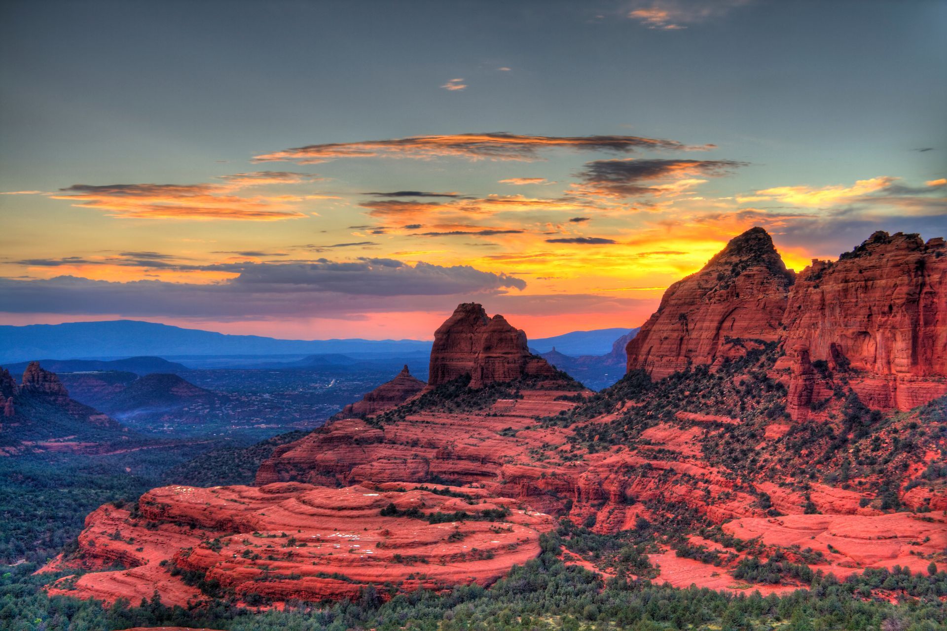 A sunset over a desert landscape with mountains in the background.