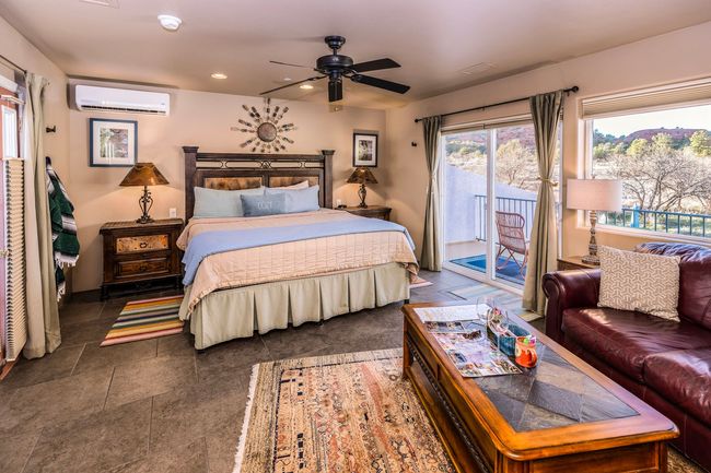 A bedroom with a king size bed , a couch , a coffee table and a ceiling fan.