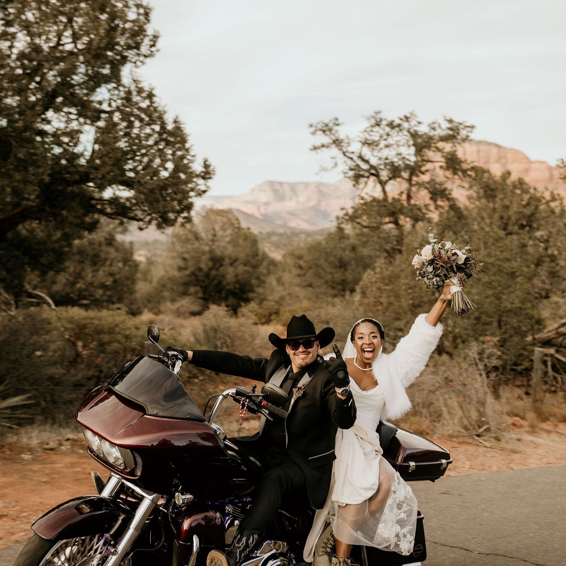 A bride and groom are posing for a picture on a motorcycle.