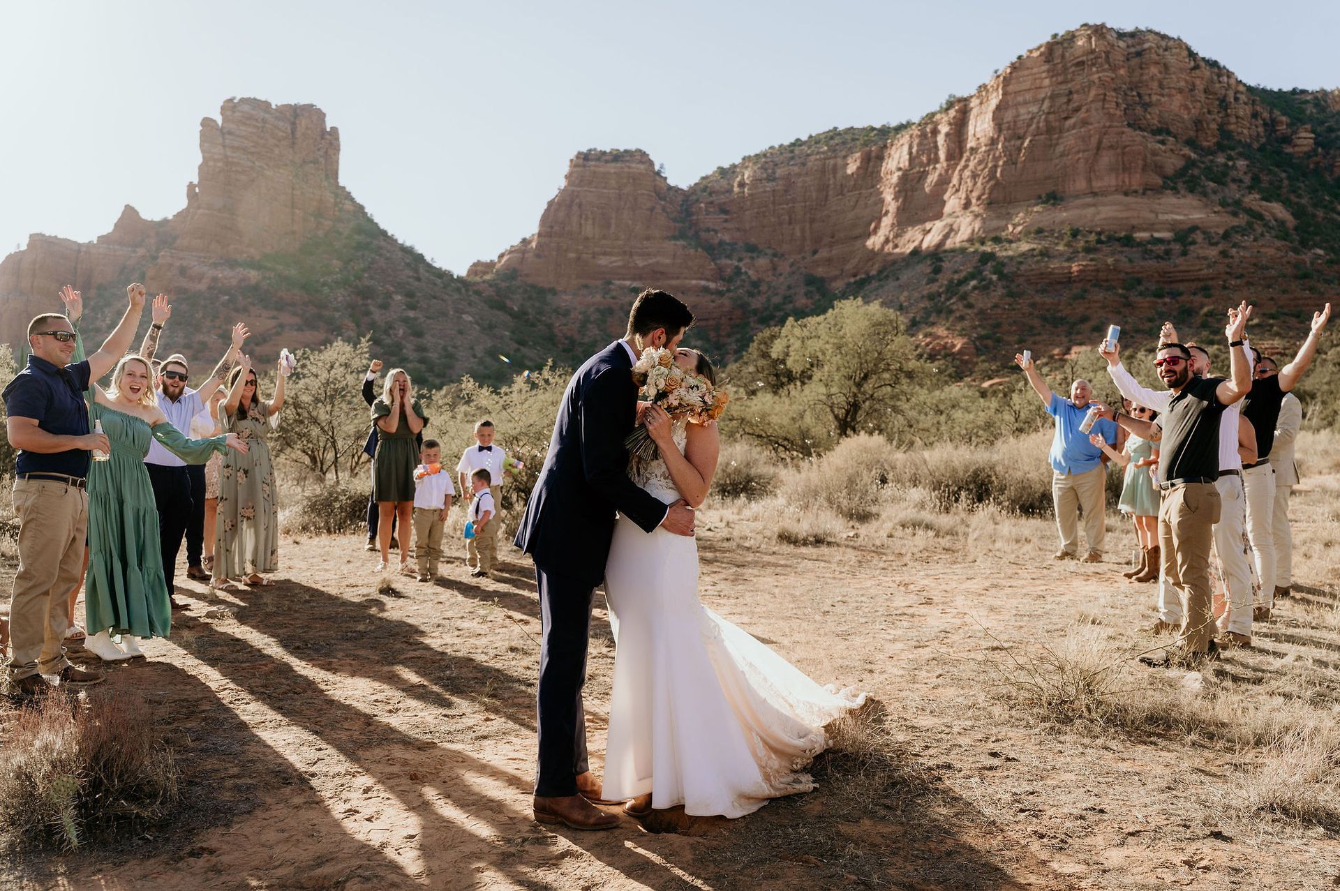 A bride and groom kissing in front of a crowd of people at their wedding.
