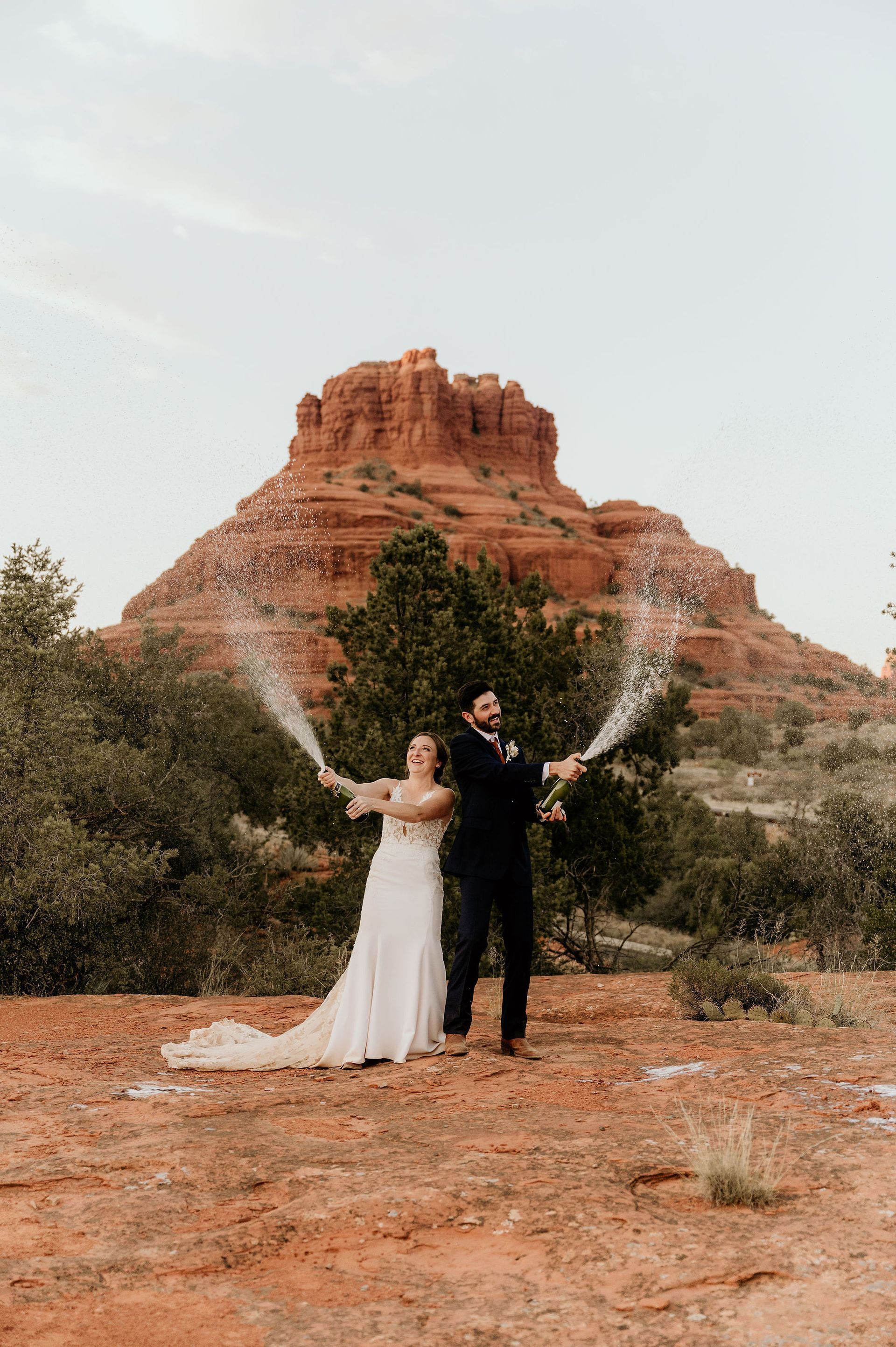 A bride and groom are posing for a picture in front of a mountain.