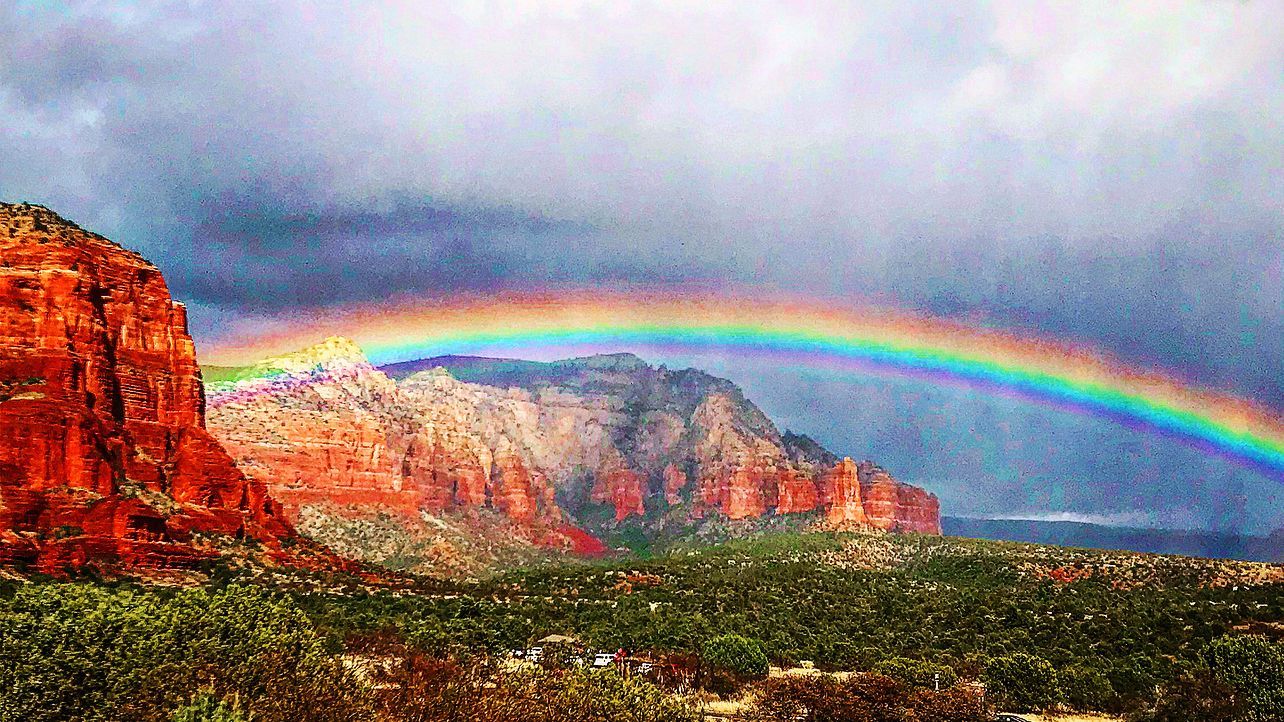 There is a rainbow in the sky over a mountain.