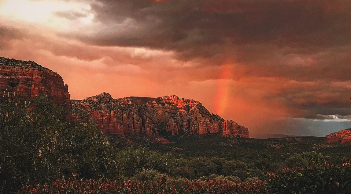 There is a rainbow in the sky over a mountain.