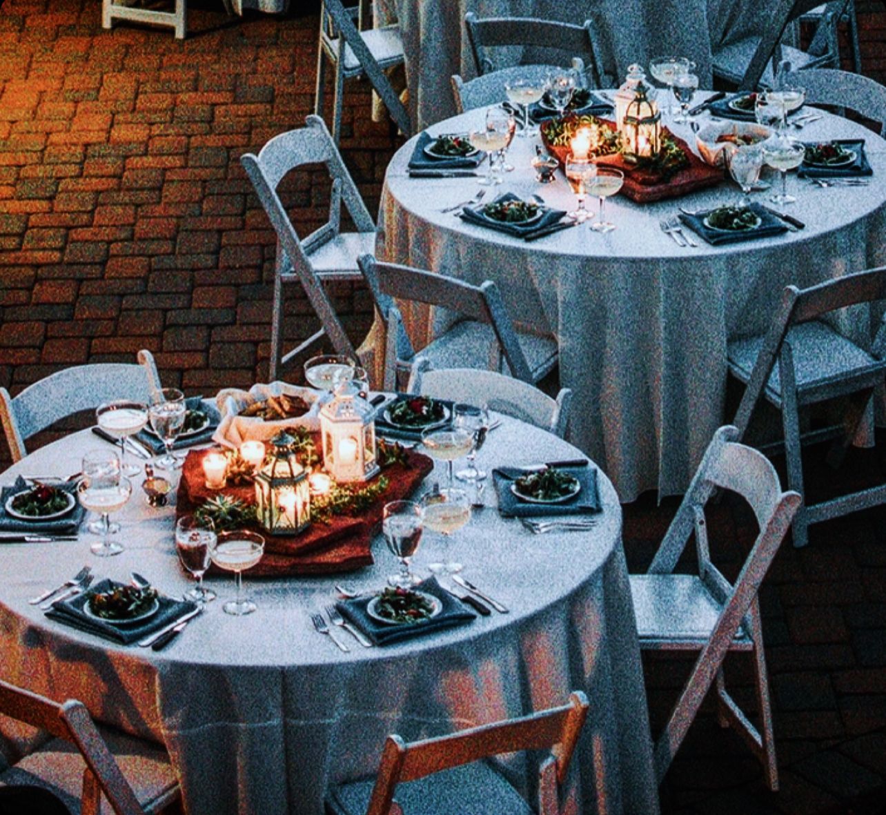 A row of tables with candles and plates on them