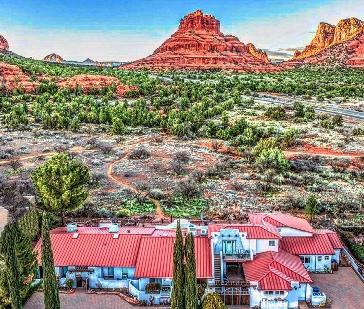 An aerial view of a large house in the desert with a mountain in the background.