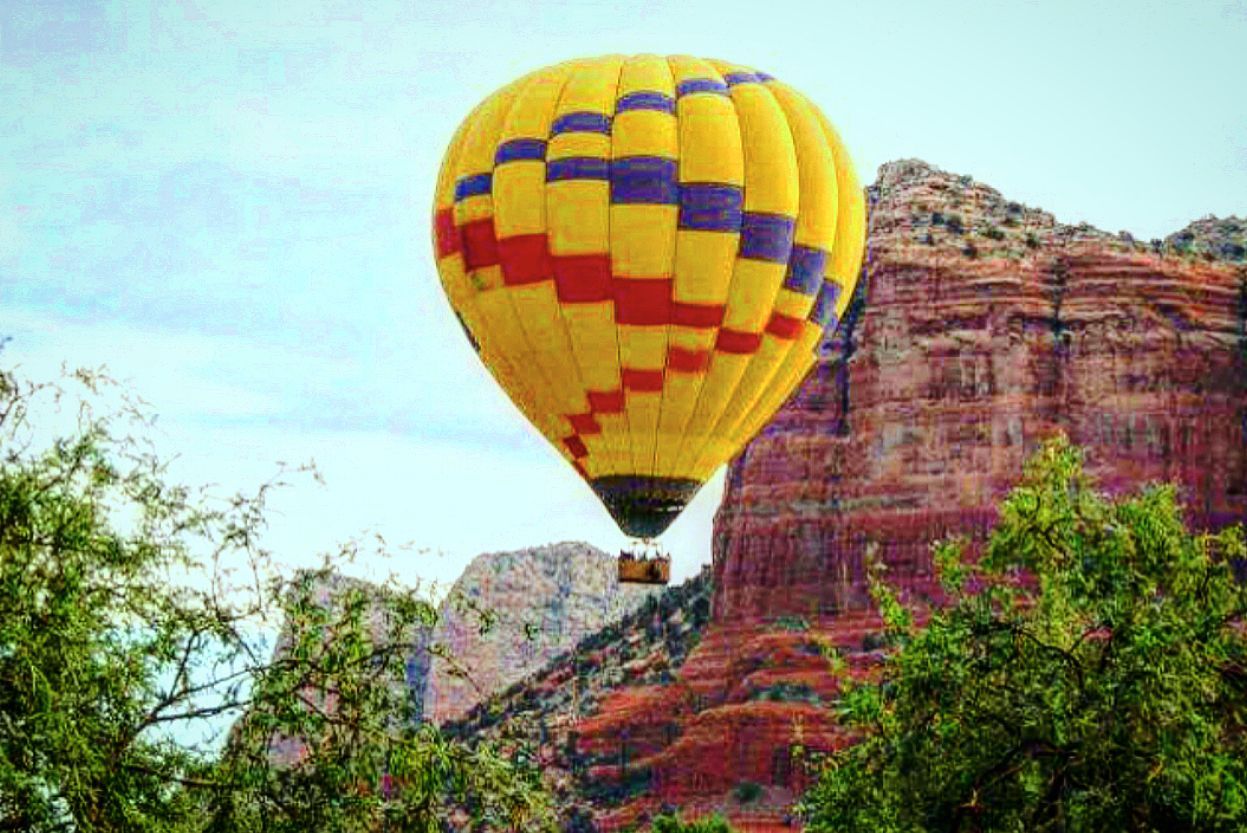 A hot air balloon is flying over a mountain.
