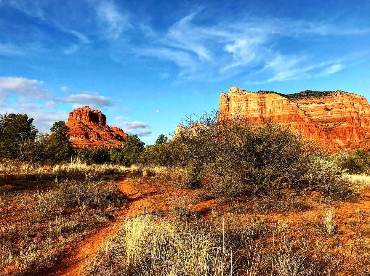 A dirt road in the desert with a mountain in the background.