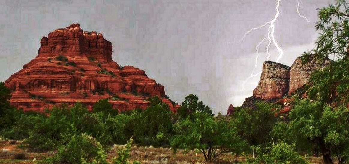 A painting of a lightning storm in the desert with a mountain in the background.