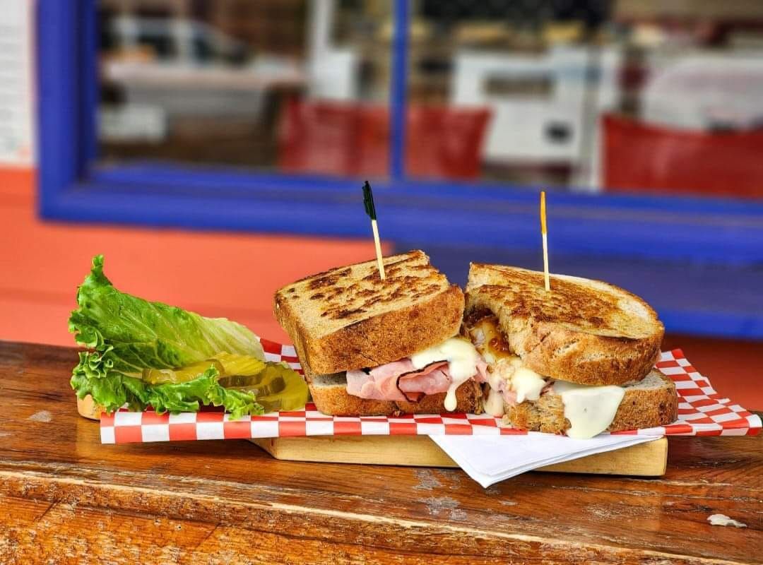 A grilled cheese sandwich is sitting on a wooden table.