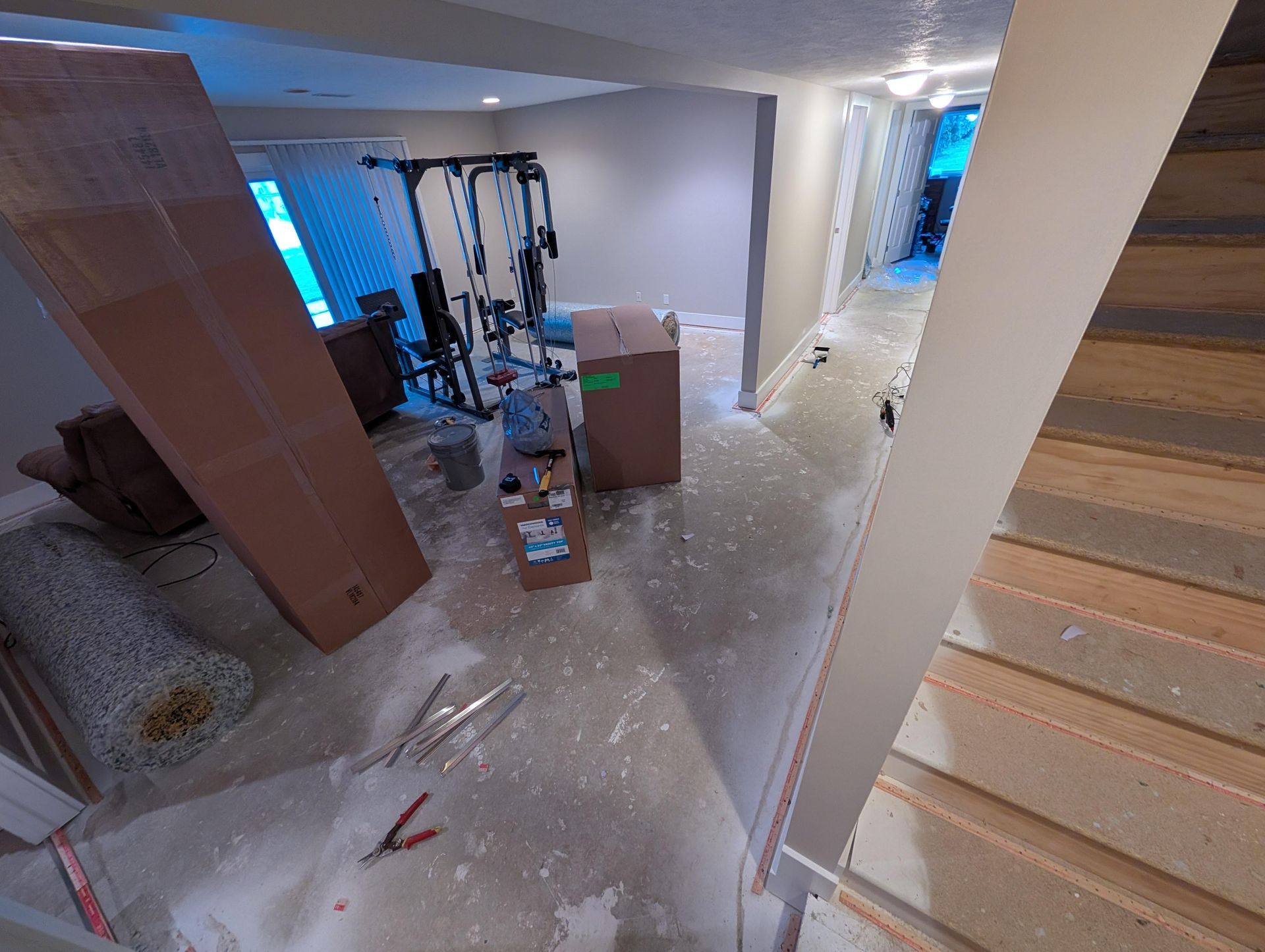 An aerial view of a basement with stairs and boxes on the floor.