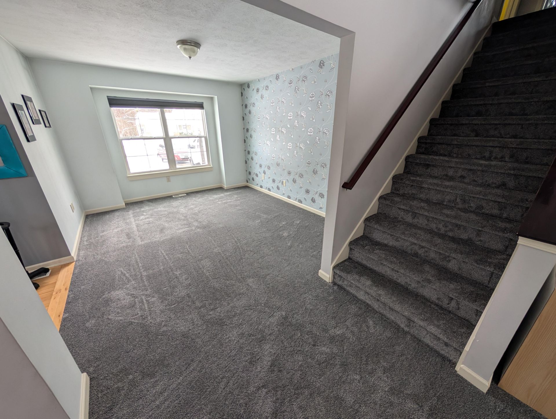 A living room with stairs leading up to the second floor.